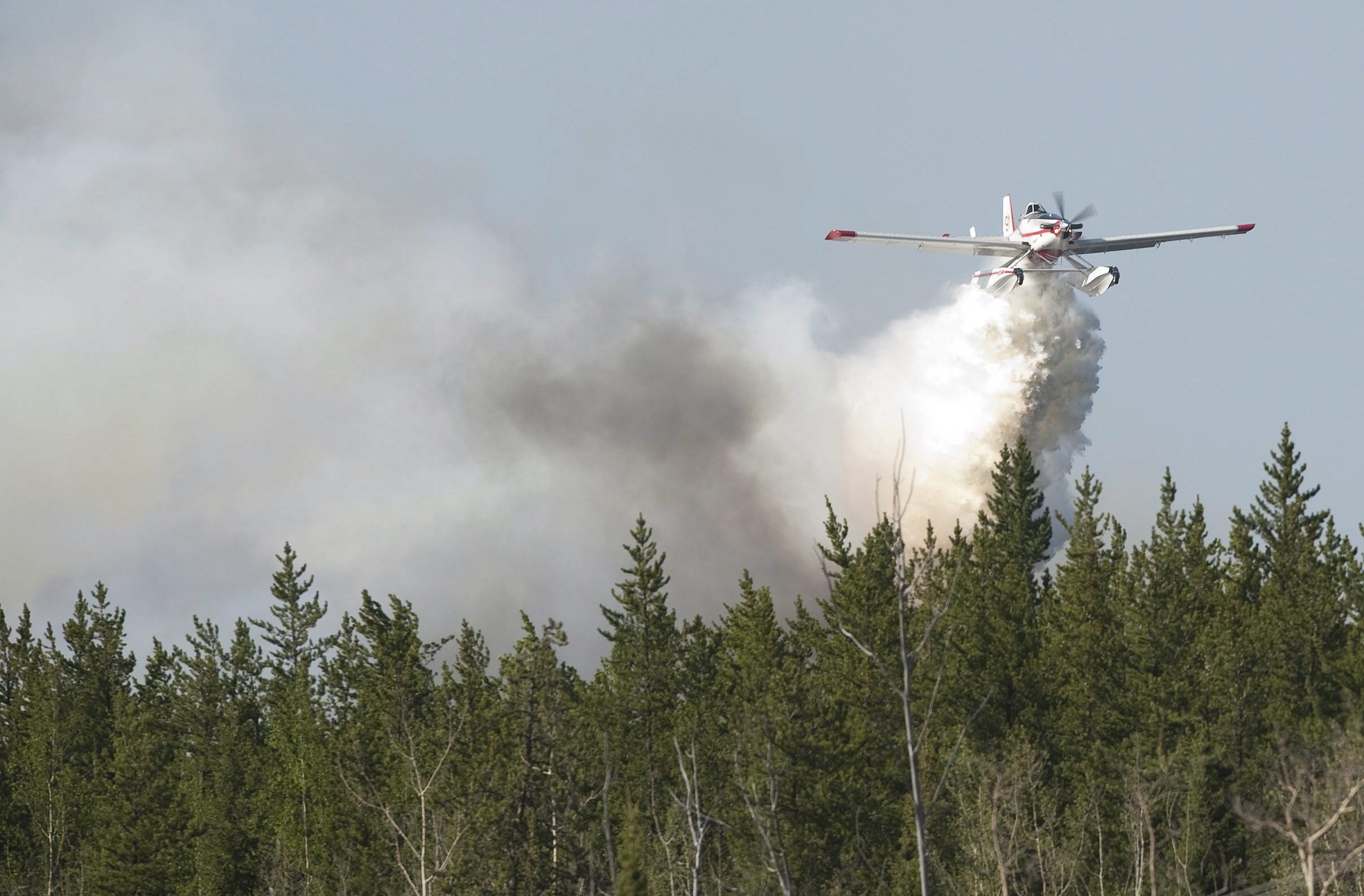 A water bomber drops its water on afire near Slave Lake, Alta. on May 15, 2011. More than 1,000 people were ordered to leave their homes when strong winds fanned two separate wildfires that burned on either side of the northern Alberta town. (Ian Jackson/The Canadian Press)