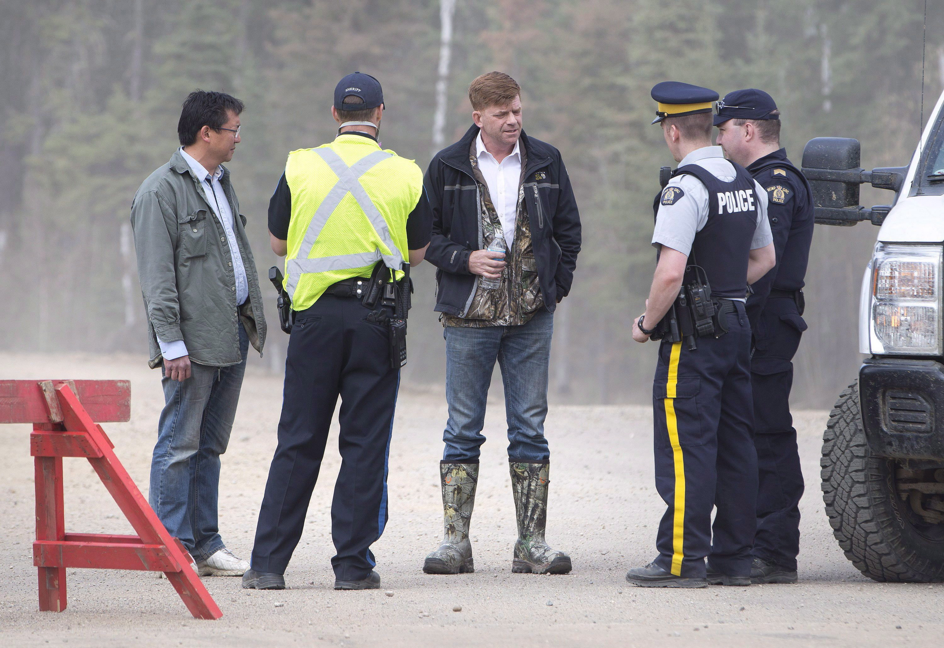 Brian Jean, centre, talks with police as the wildfire spread through  the city, incinerating hundreds of properties on May 5, 2016. (Jason Franson/The Canadian Press)