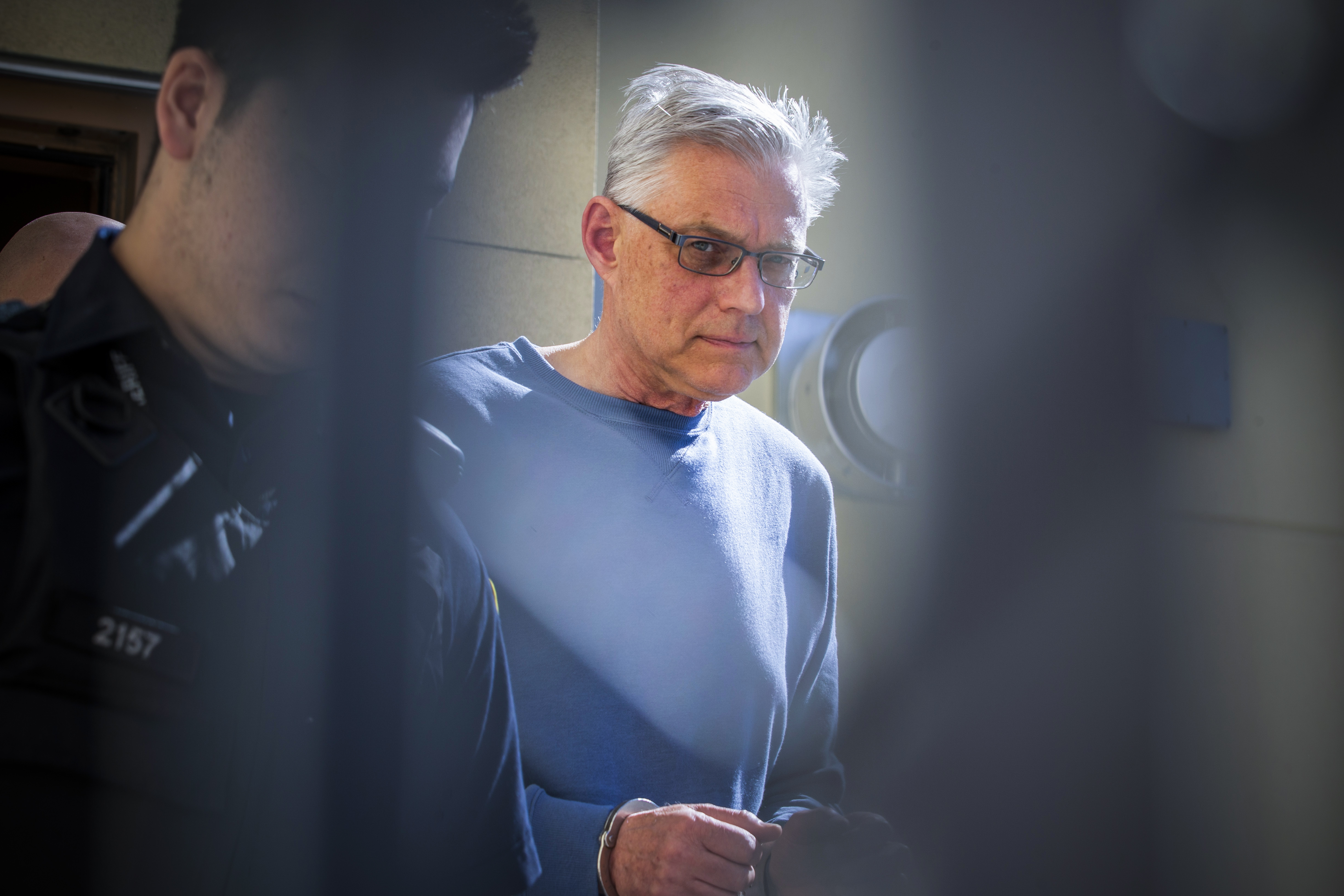 John Brittain, 68, is escorted in police custody at the Penticton Courthouse on April 16, 2019. Brittain was charged with three counts of first-degree murder and one count of second-degree murder in a Penticton shooting. (Ben Nelms/CBC)