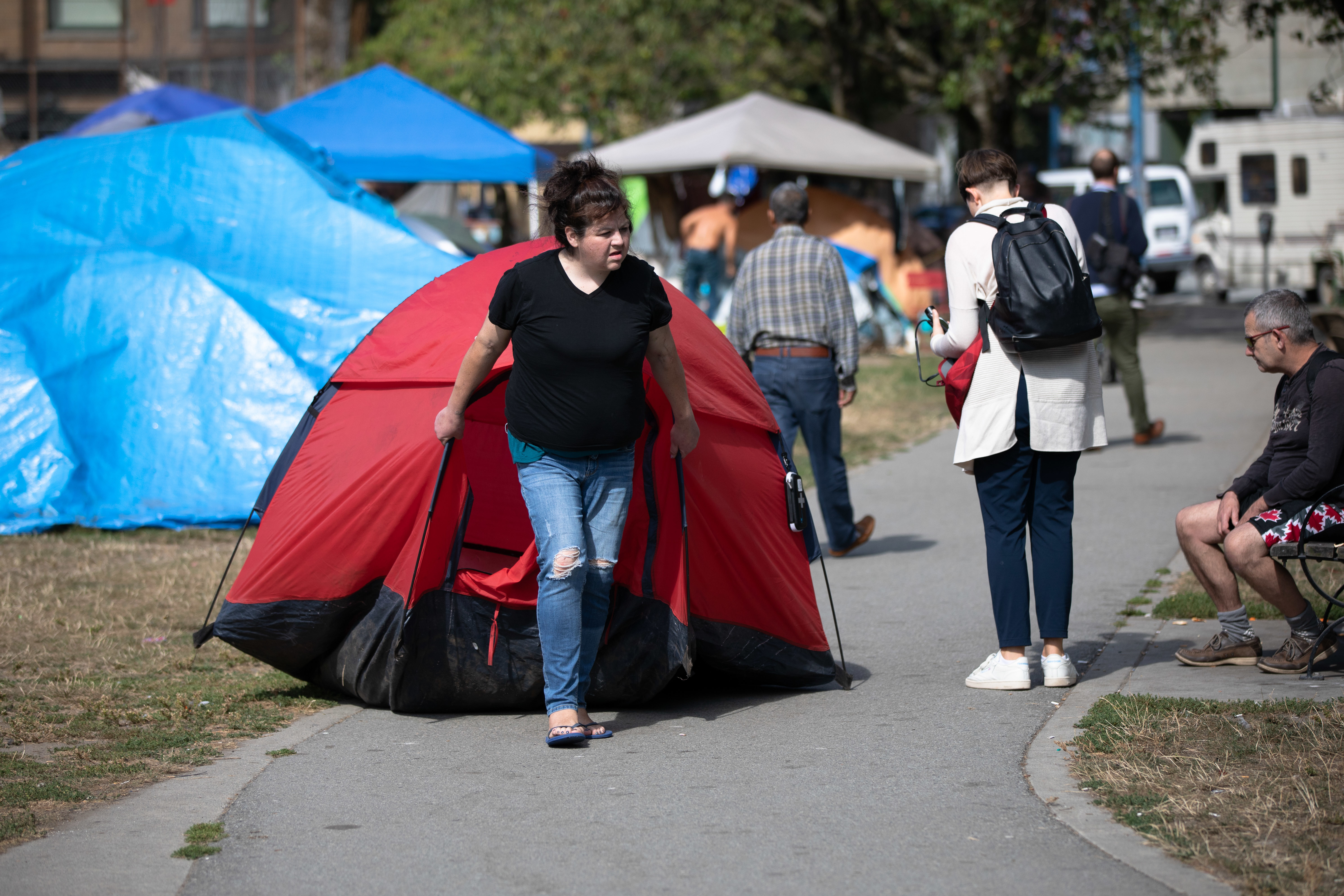 A woman drags her tent to a new area of the homeless camp in Vancouver's Oppenheimer Park on Aug. 19, 2019. (Maggie MacPherson/CBC)