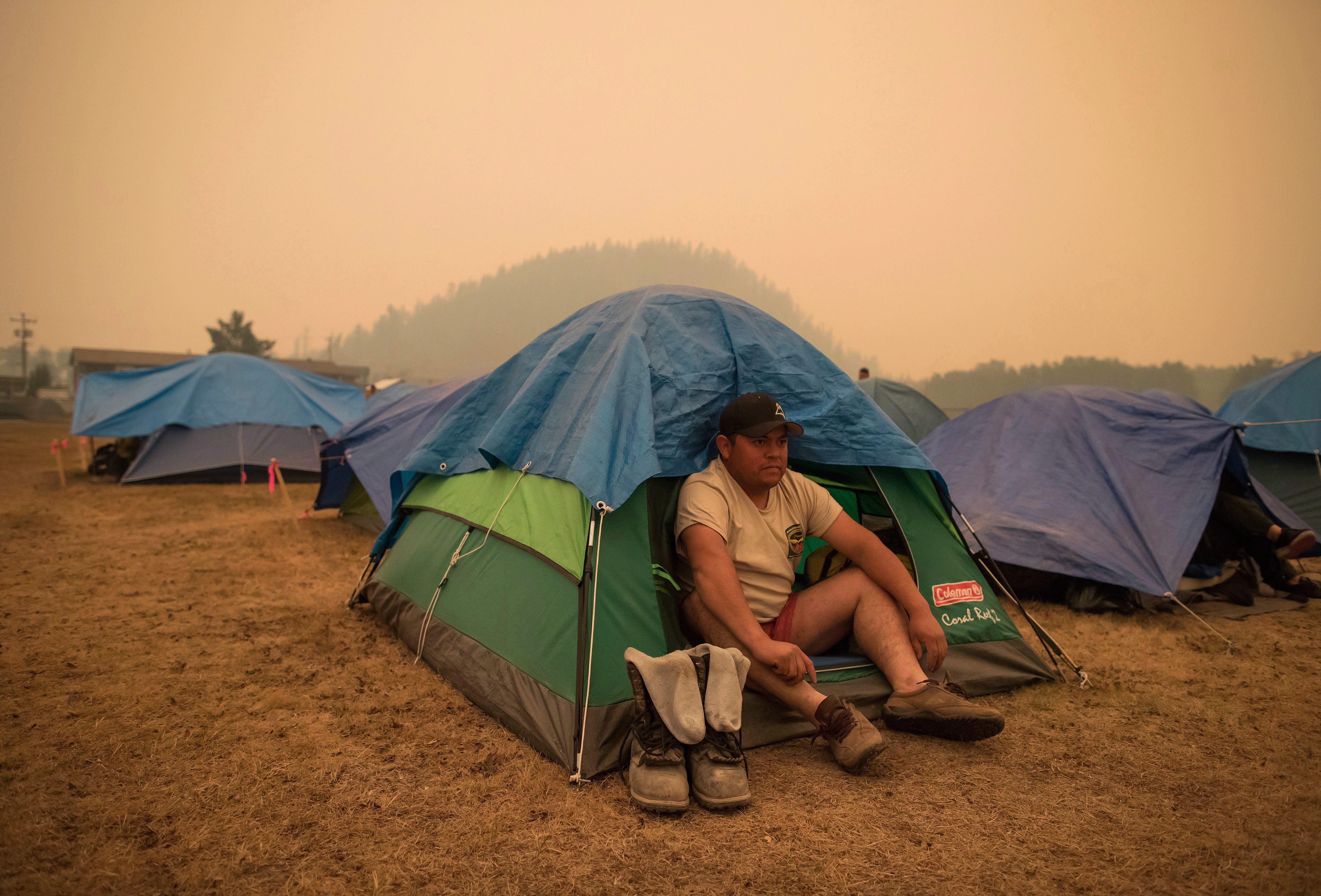 Wildland firefighter Raymundo Rosales of Mexico sits outside his tent in Fraser Lake, B.C., on Aug. 22, 2018. (THE CANADIAN PRESS/Darryl Dyck)