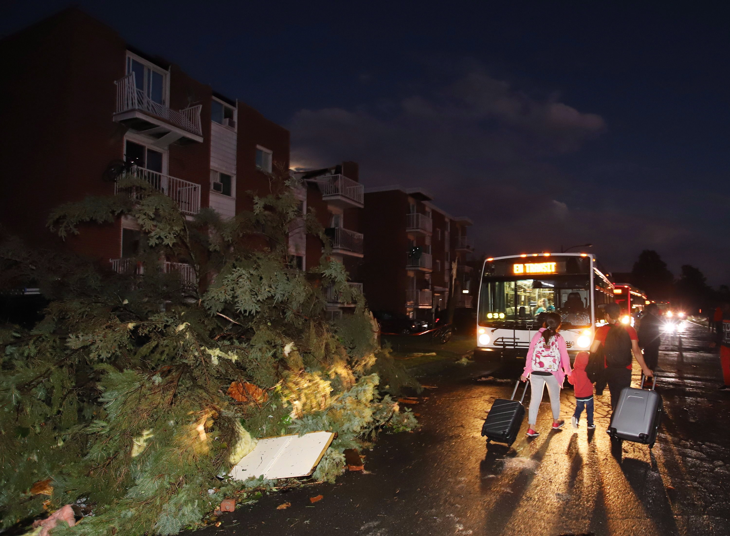 Residents board buses after the roofs of apartment buildings were torn off and windows were blown out in the Gatineau neighbourhood of Mont-Bleu. (Fred Chartrand/Canadian Press)