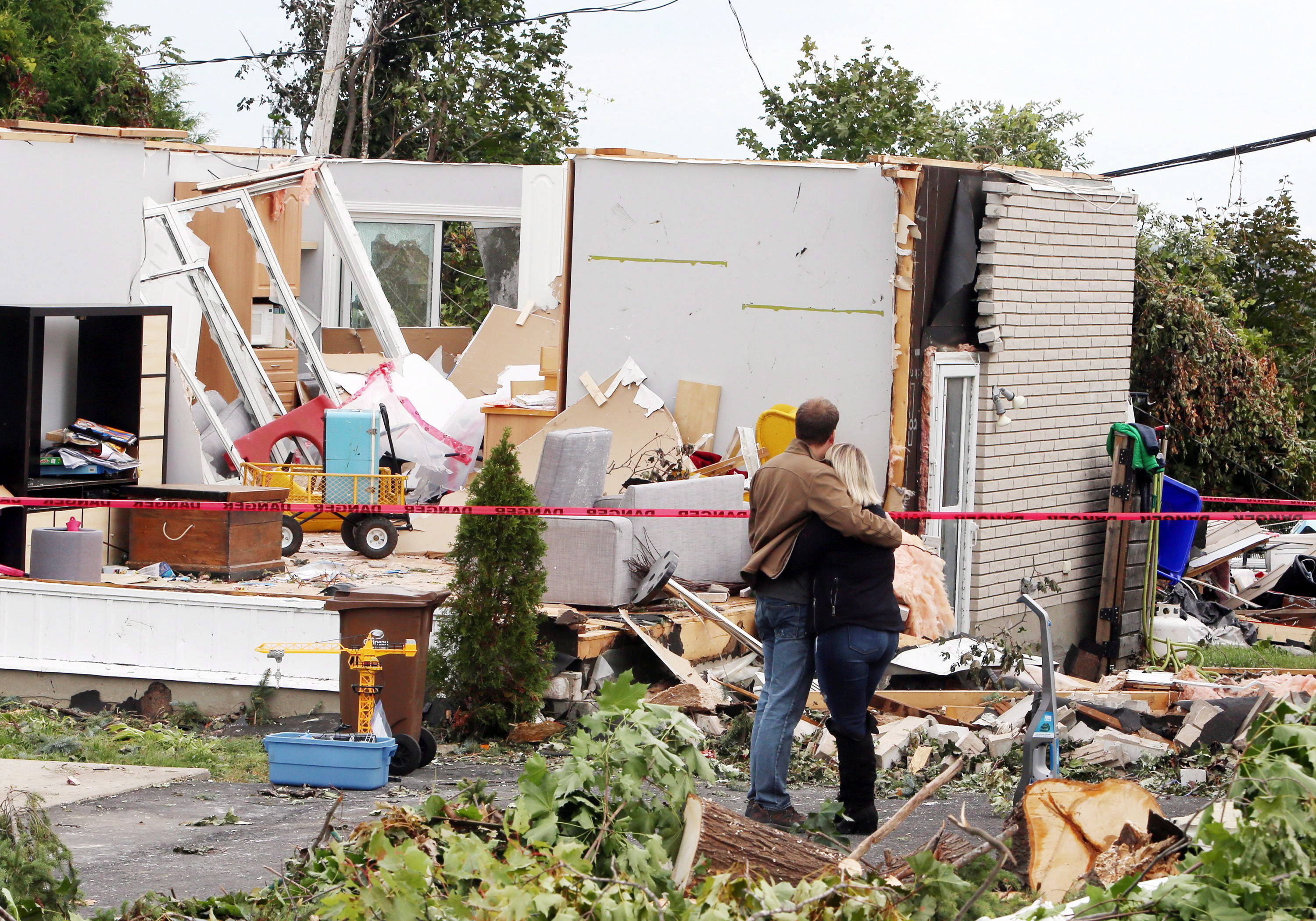 A man and woman embrace as they survey the damage to a home in Gatineau on Sept. 23. (Fred Chartrand/Canadian Press)