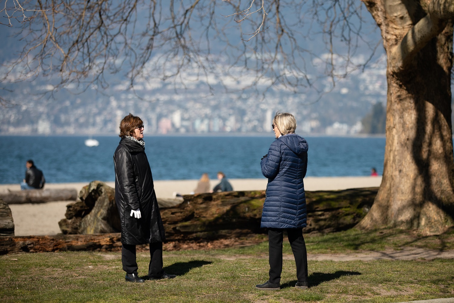 Two people speak while practicing social distancing at Kitsilano Beach in Vancouver on Wednesday, March 18, 2020. (Maggie MacPherson/CBC)