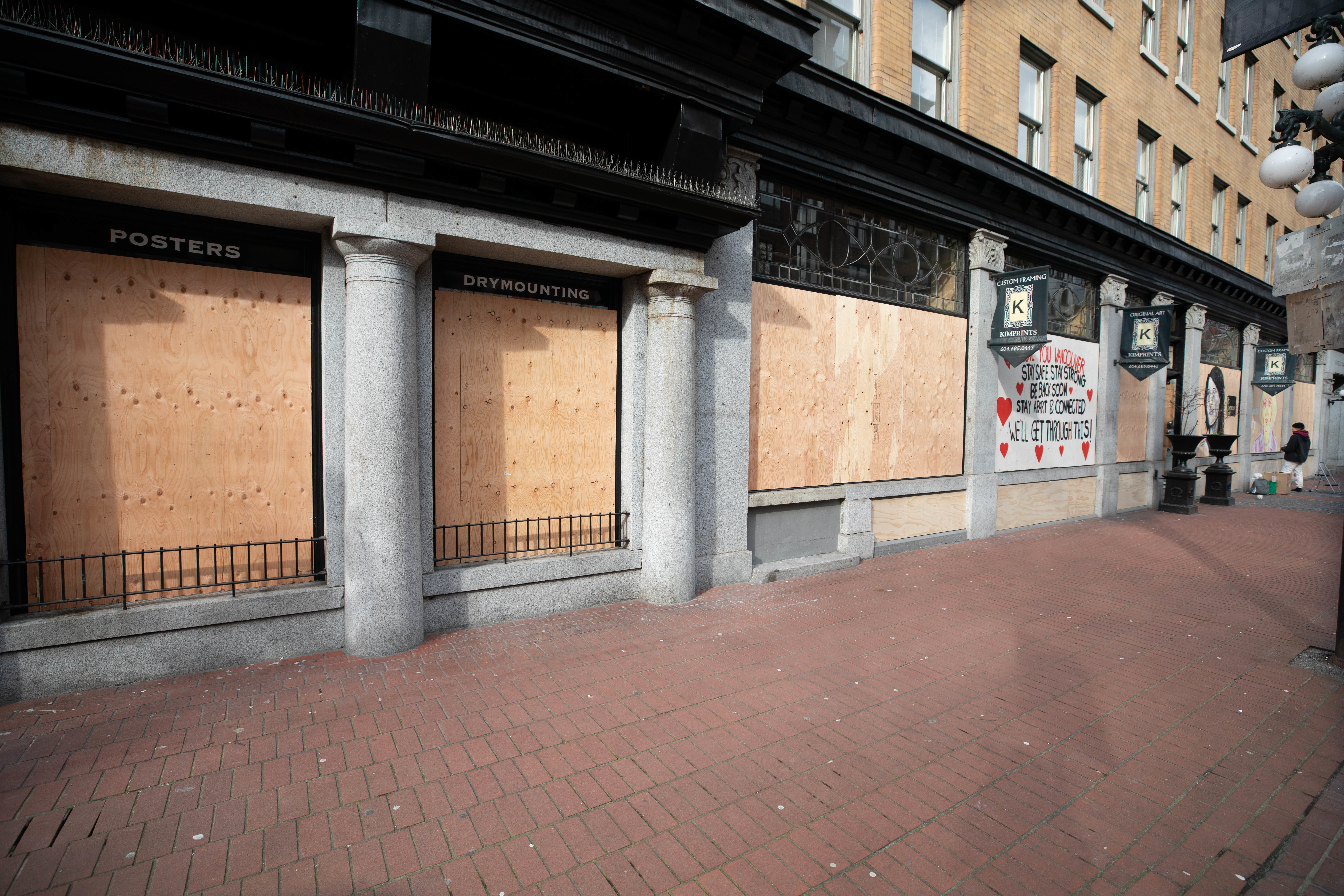 Mostly blank boards cover the windows of Kimprints in Vancouver on March 31. 