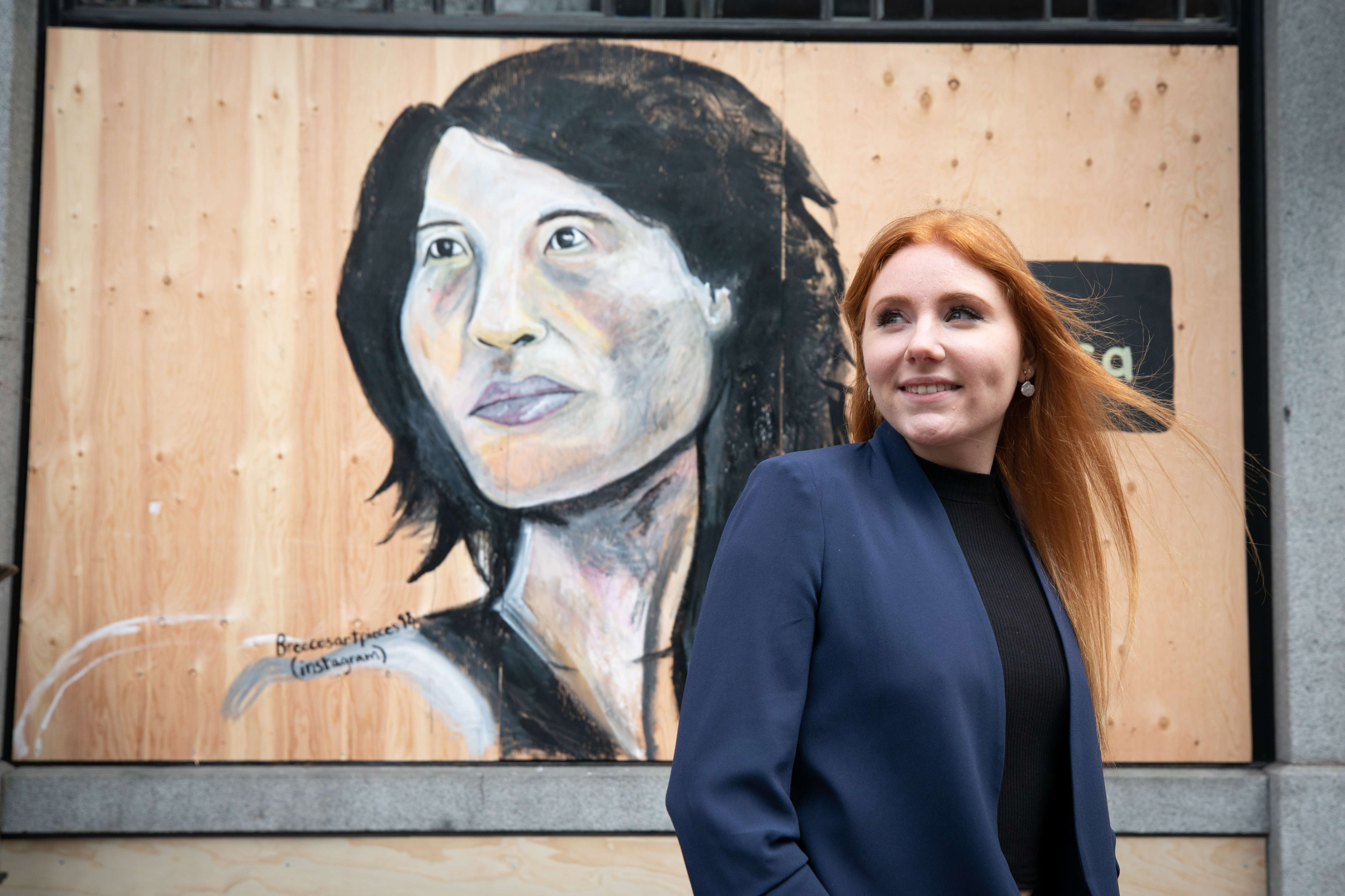 Artist Breece Austin stands in front of a mural she painted of Canada's chief public health officer Dr. Theresa Tam.