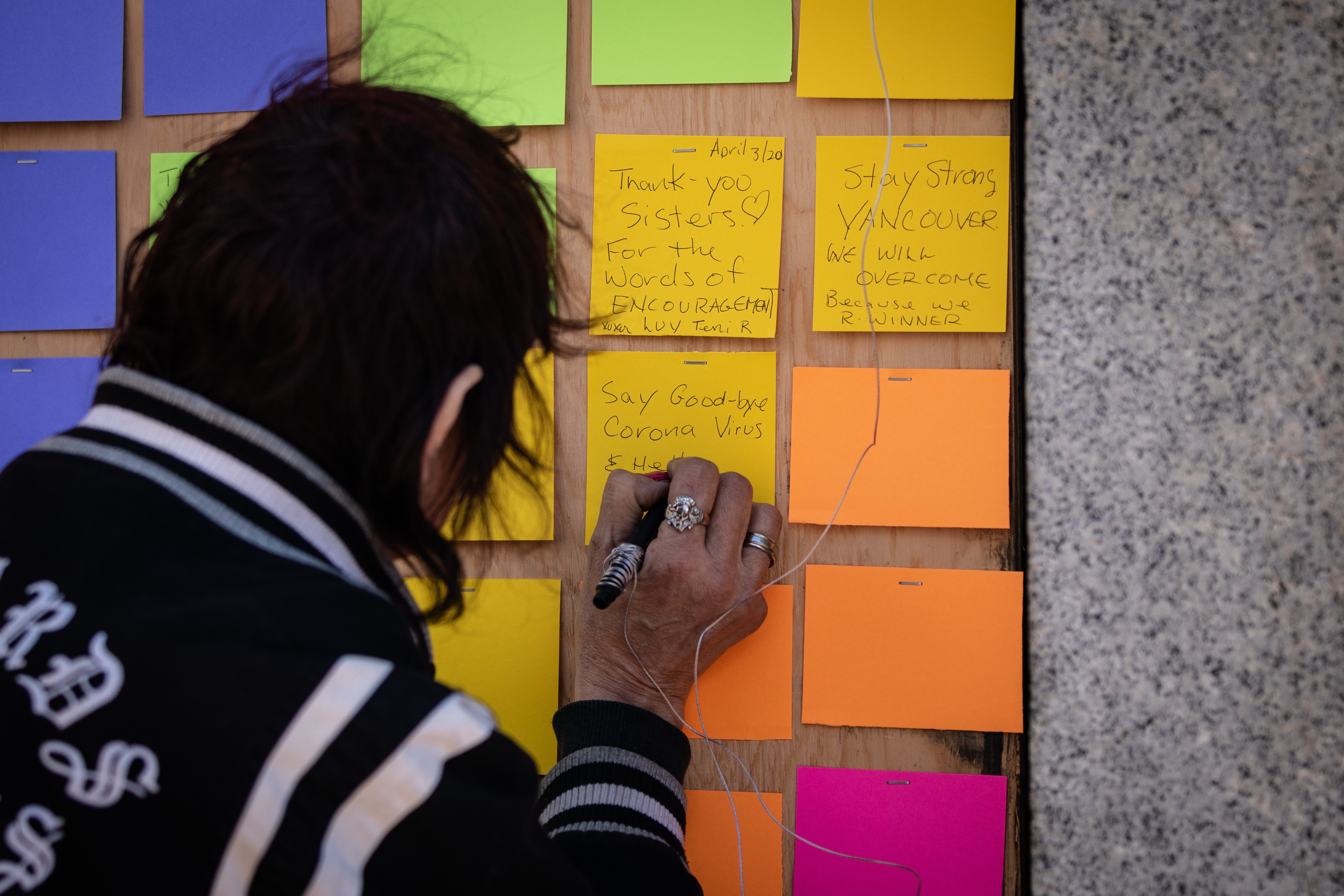 A woman writes, 'Say goodbye coronavirus and hello Corona beer, thanx' on a sticky note. 