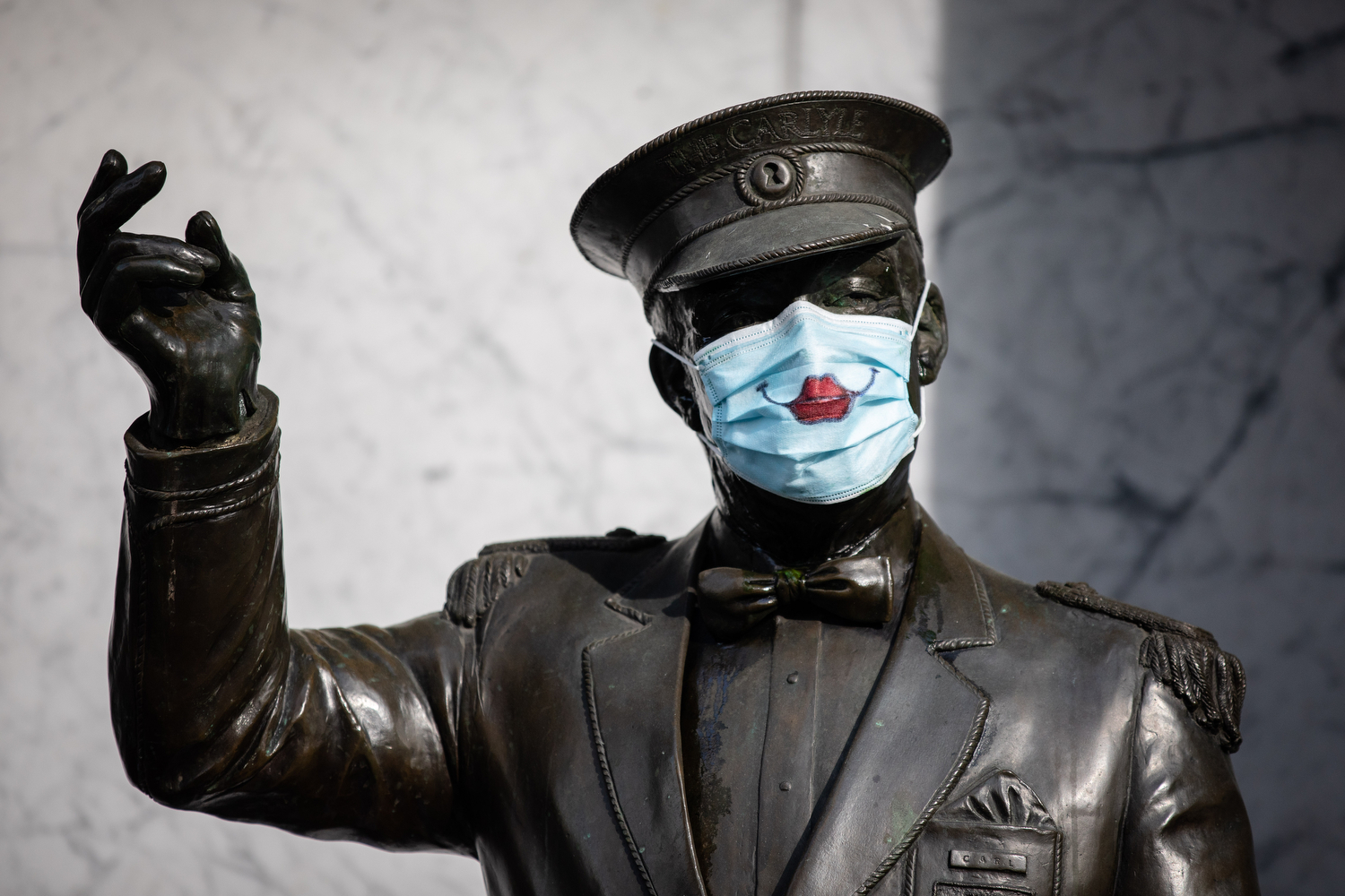 Statue wearing a mask with smiling painted lips is pictured outside of Carlyle Apartments in Vancouver on April 27, 2020. (Maggie MacPherson/CBC)