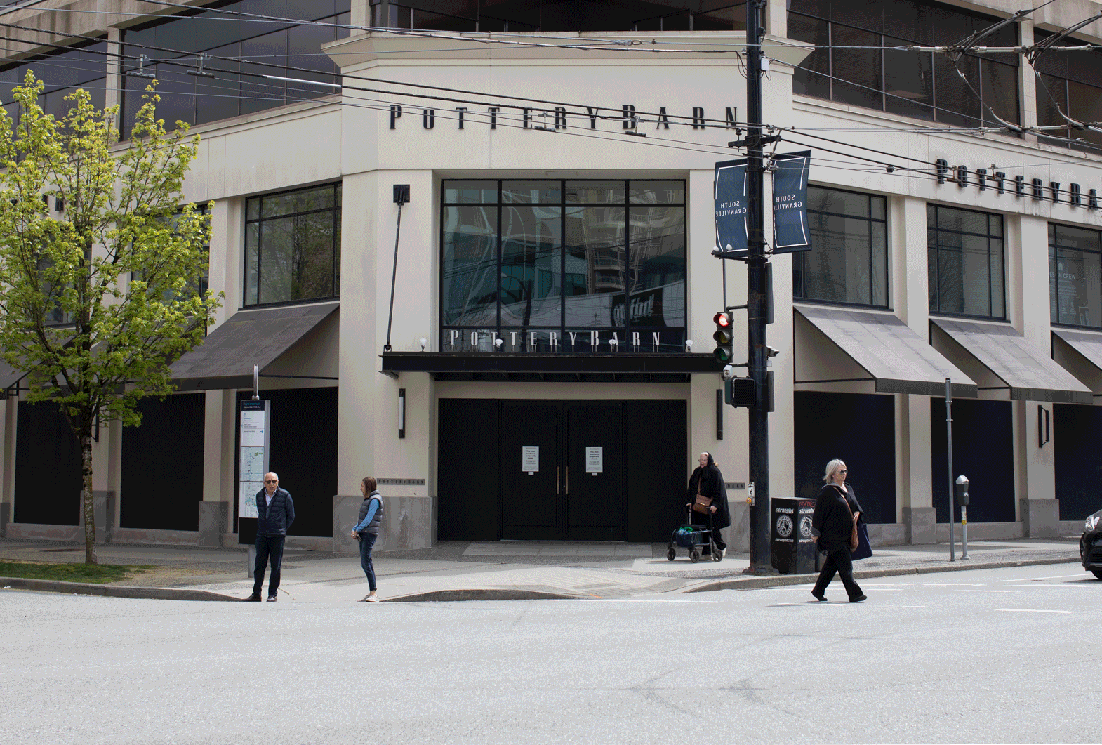 A mural by artist Ben Knight reads "Woven by love" on a boarded-up Pottery Barn storefront on South Granville Street.