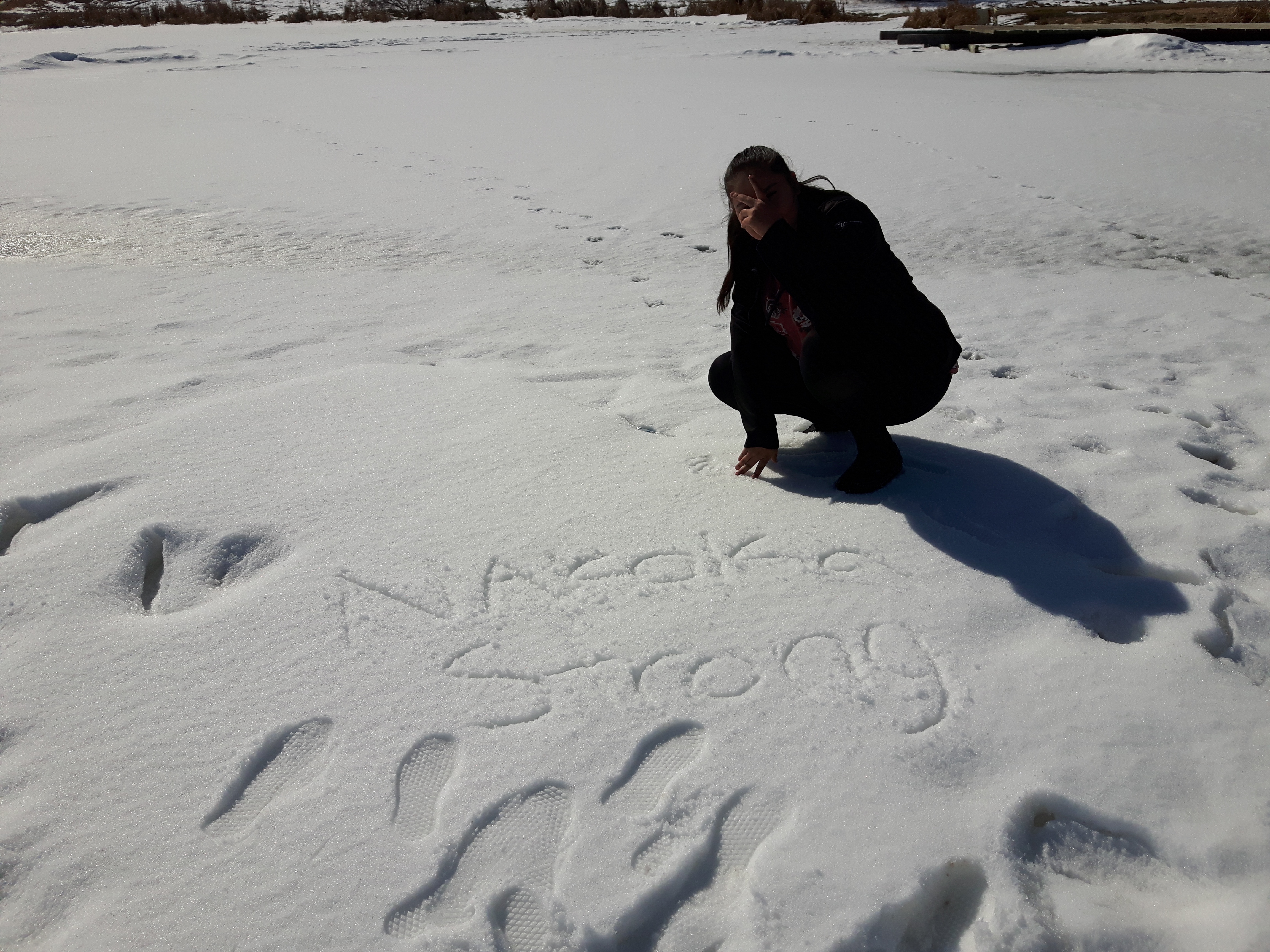 A picture of Nessa, who has asked we not use her last name. She's covering her face, but at her feet, it says 'Nakota Strong.'