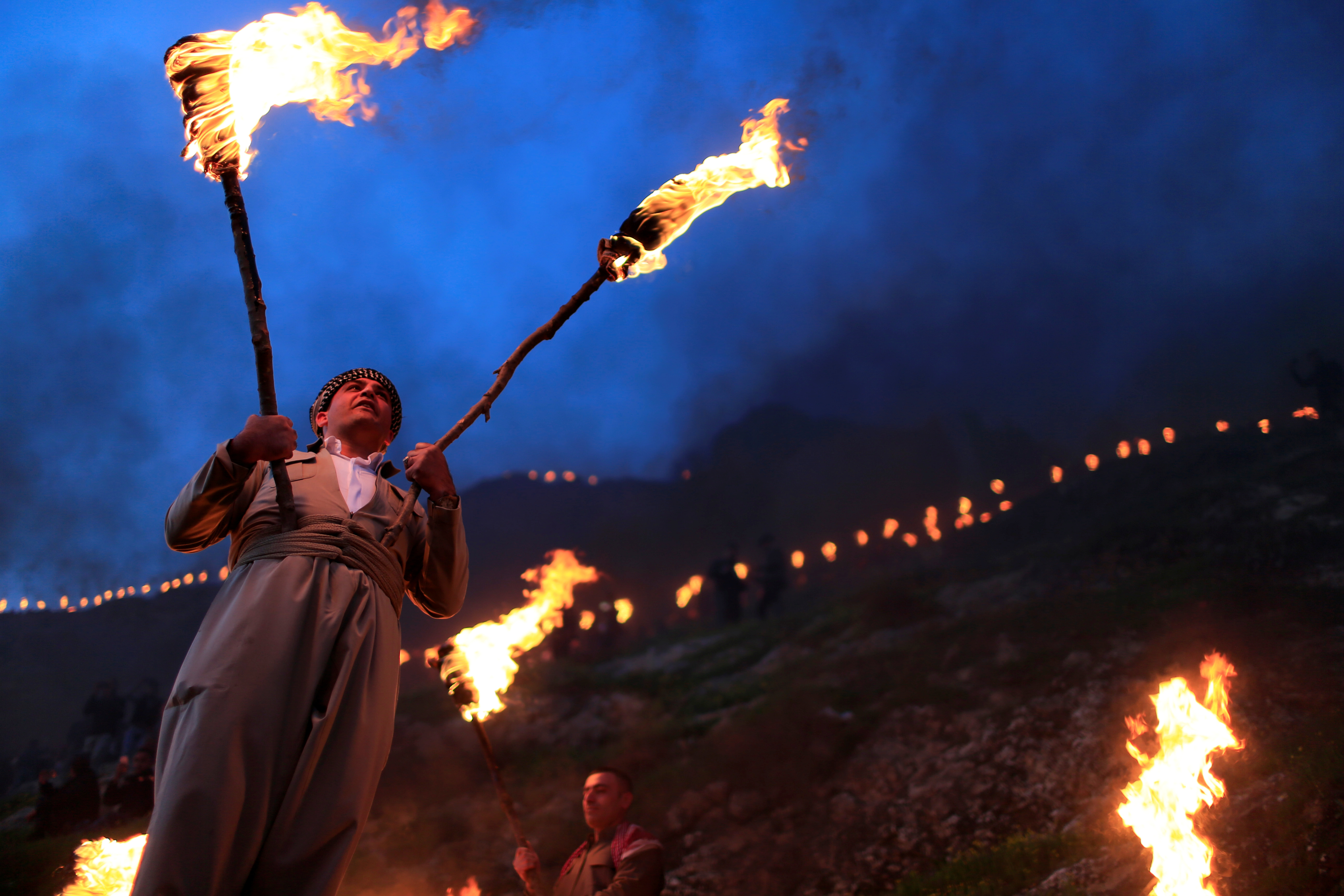 A Kurdish Iraqi man carries fire torches, as he celebrates Nowruz Day in the town of Akra near Duhok, in Iraqi Kurdistan on March 20, 2019. (Thaier Al-Sudani/Reuters)