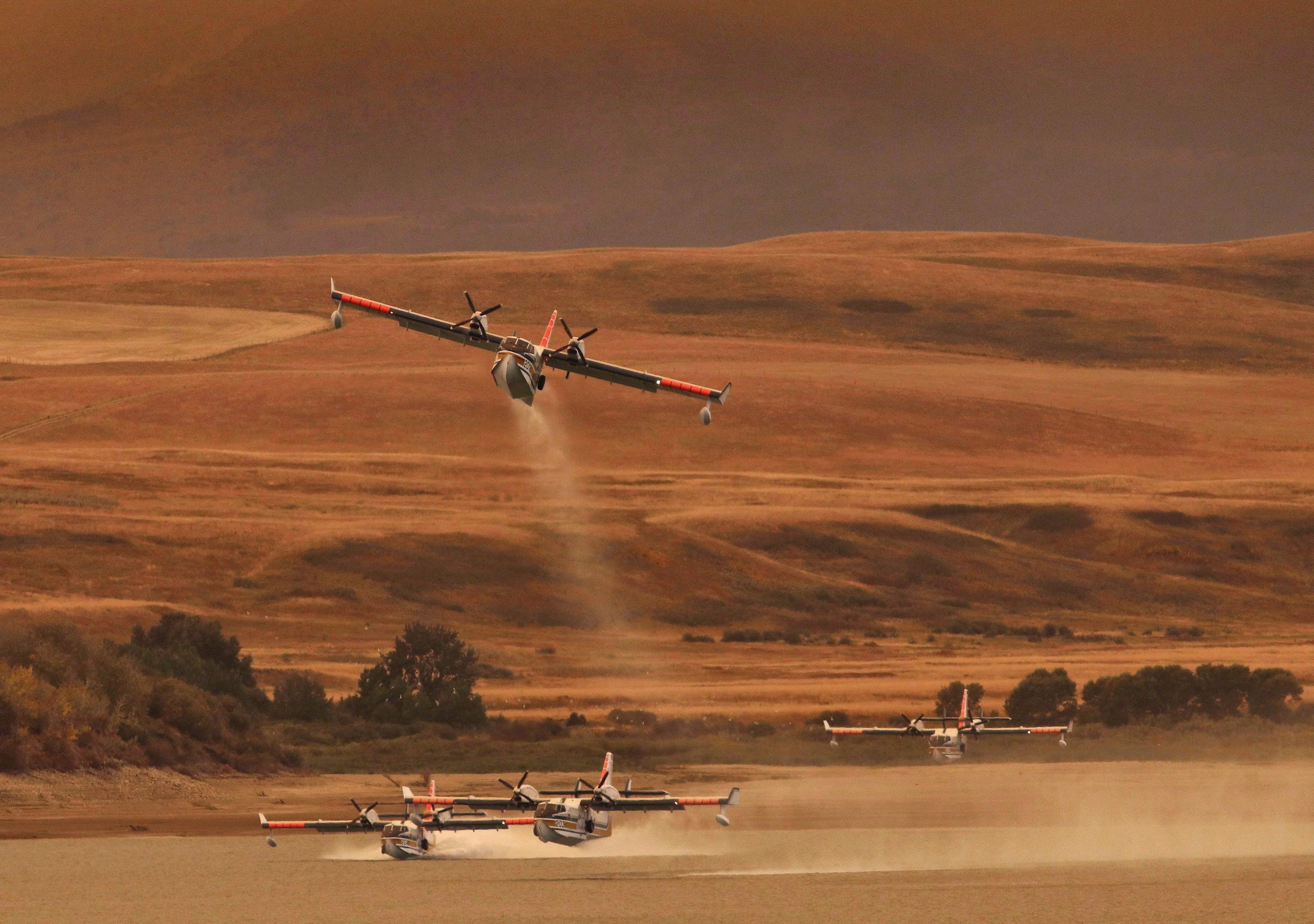 Water bombers pick up water at the Waterton Dam, north of Waterton Lakes National Park, Alta., on Sept. 12, 2017, adding to the fight against a large fire burning in the park. (David Rossiter/The Canadian Press)