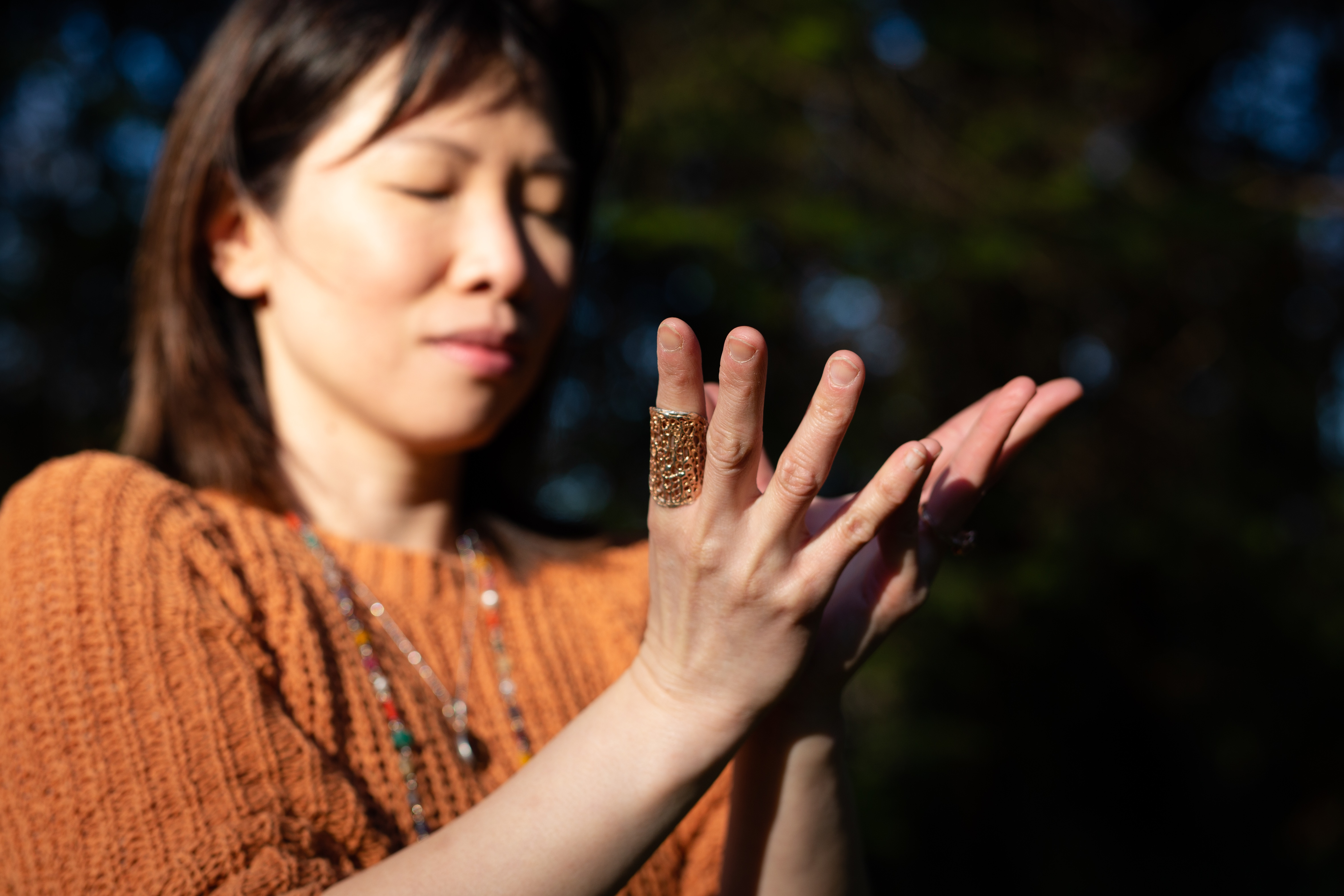 Yoga therapist Zoe Ho puts her hands in lotus mudra, a hand gesture symbolizing light and beauty emerging from the darkness. 