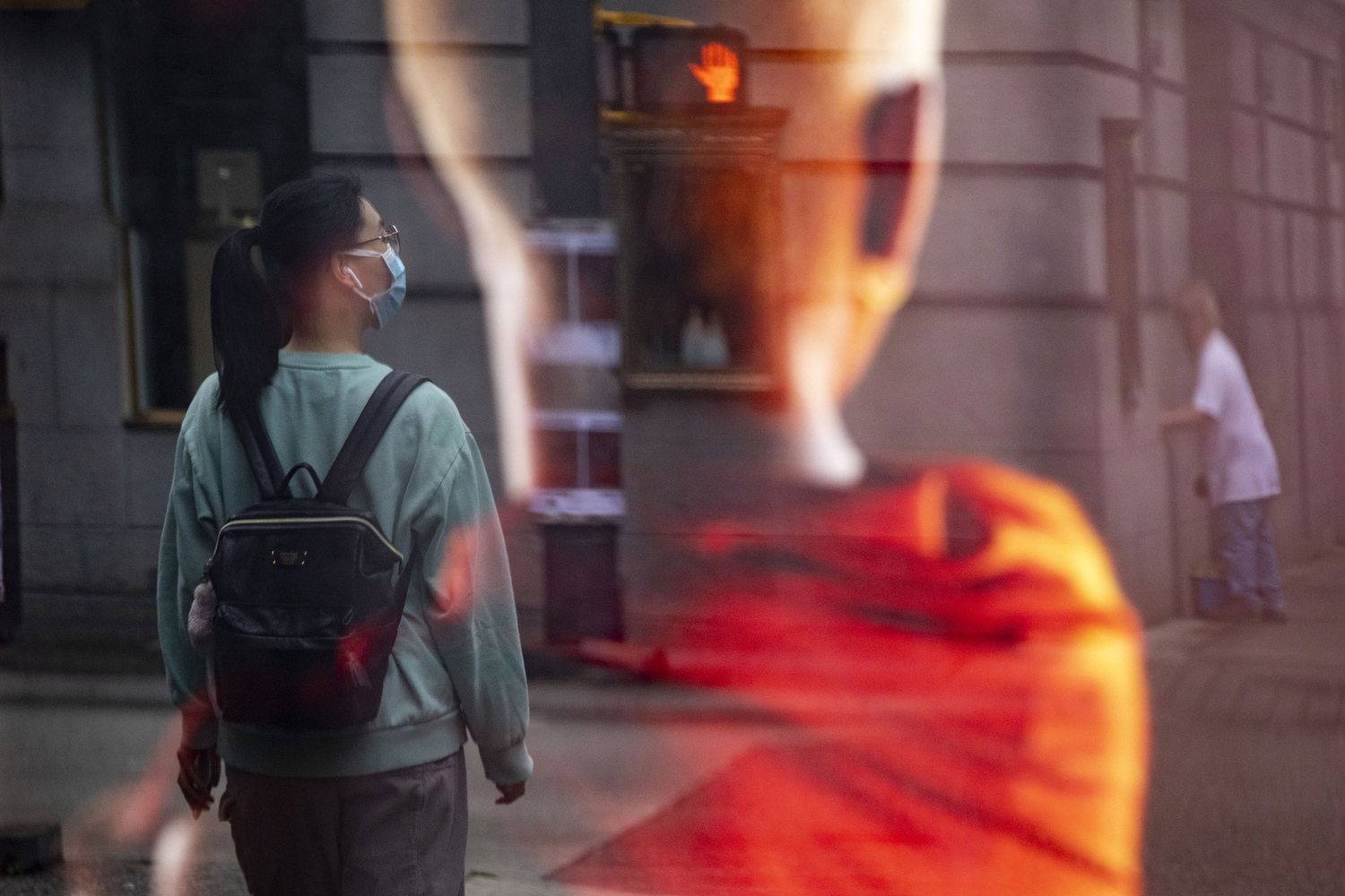 A woman wearing a surgical mask is pictured in a reflection from an advertisement in downtown Vancouver on Aug. 6, 2020. (Ben Nelms/CBC Vancouver)