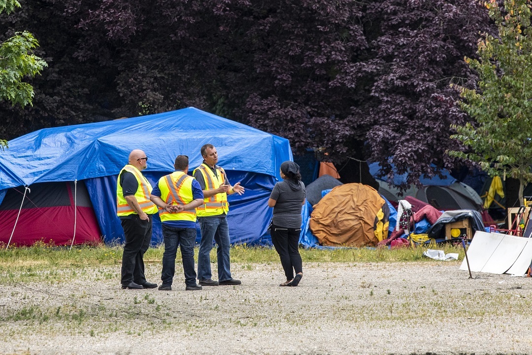 City of Vancouver workers speak with camp liasion Chrissie Brett in August. Since summer, Vancouver police say the number of calls for service at the park have increased. (Ben Nelms)