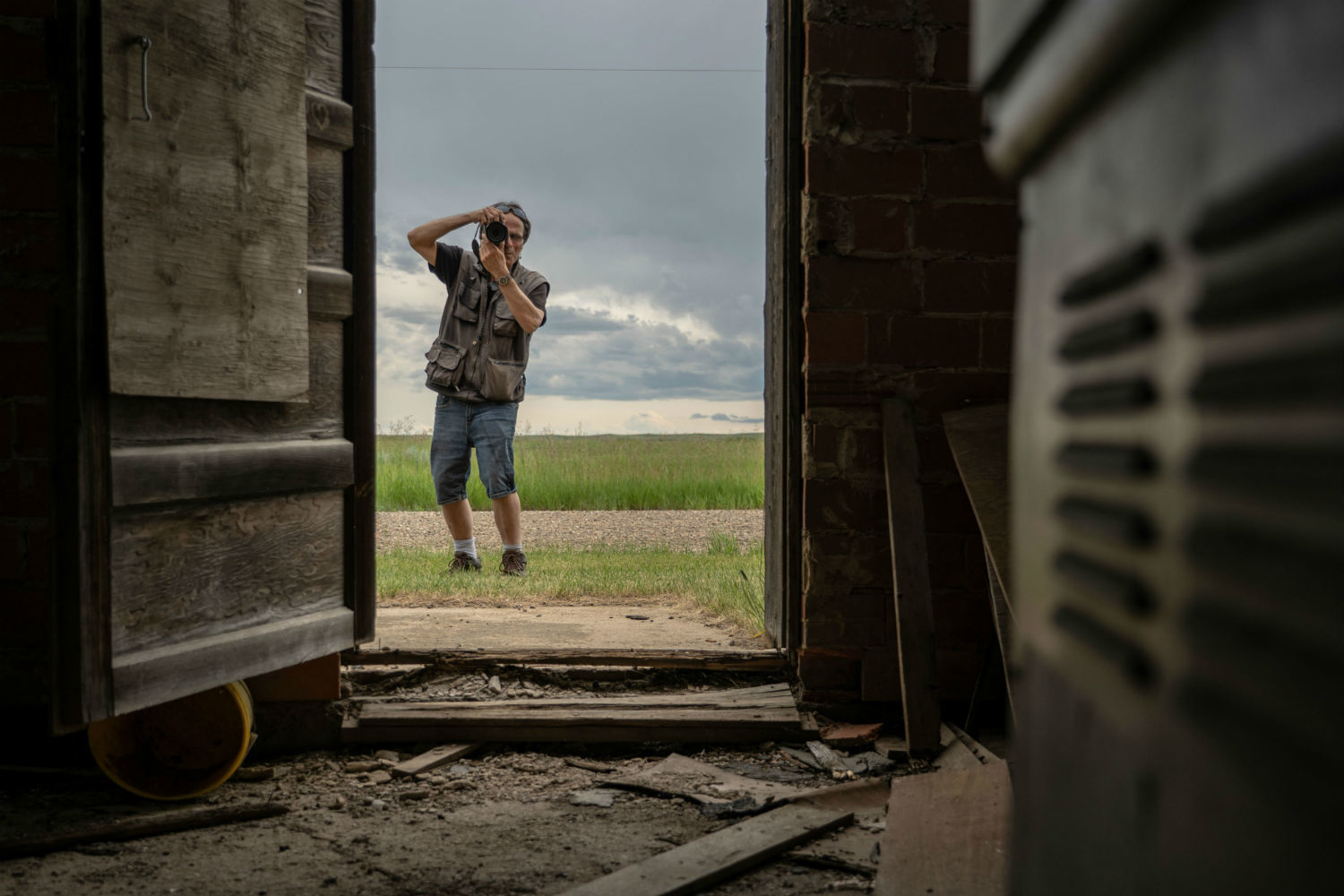 Johnnie Bachusky photographs a building through a doorway in Nemiskam, Alta. (Vincent Bonnay/Radio-Canada)