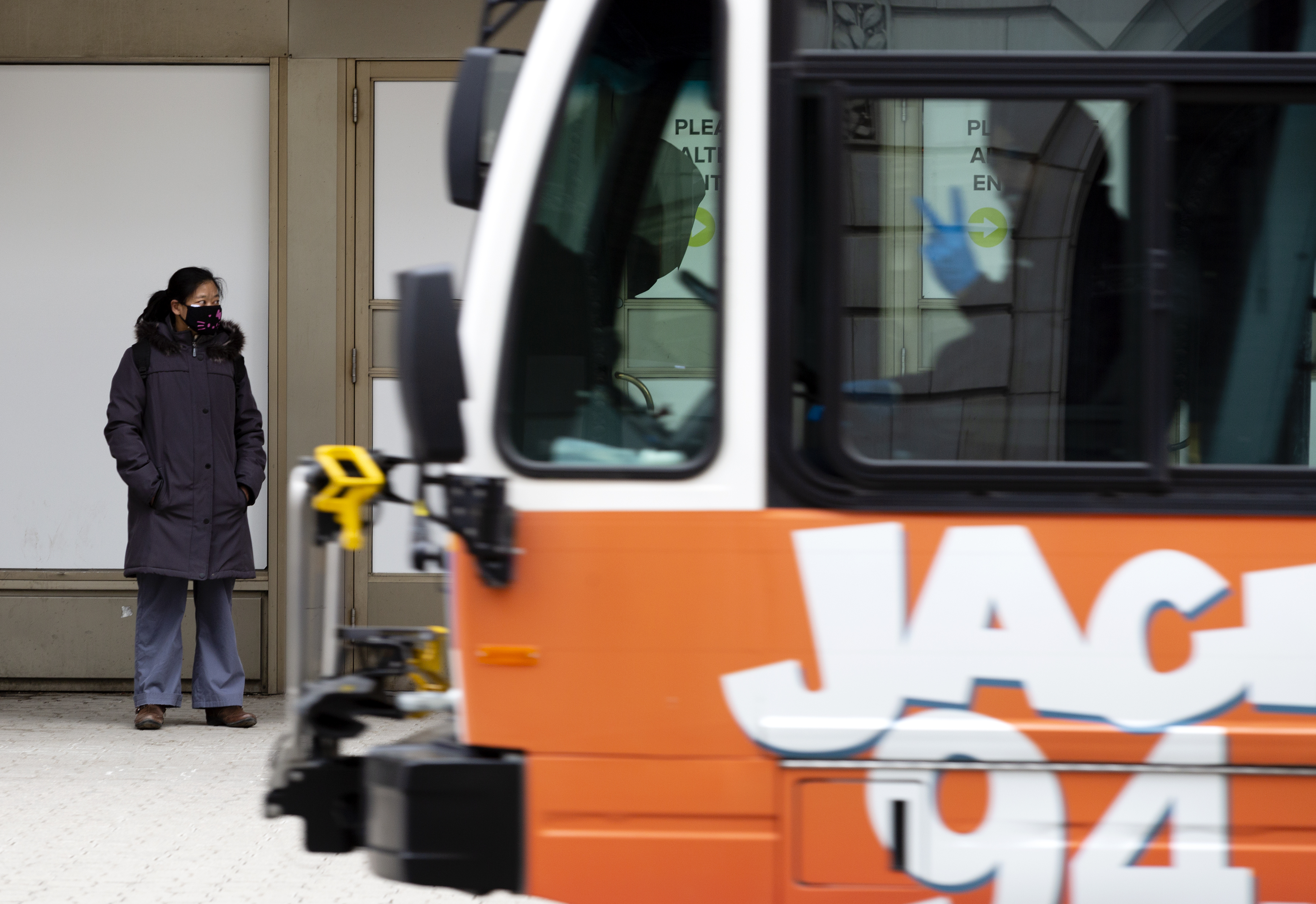 A bus driver flashes a peace sign while a woman wearing a mask waits for a bus in Regina’s downtown. Transit drivers are wearing more personal protective equipment, including gloves and masks. Still, people are wary of hopping on. The city said ridership numbers had dropped roughly 16,000 per weekday by March 20. (Bryan Eneas/CBC)