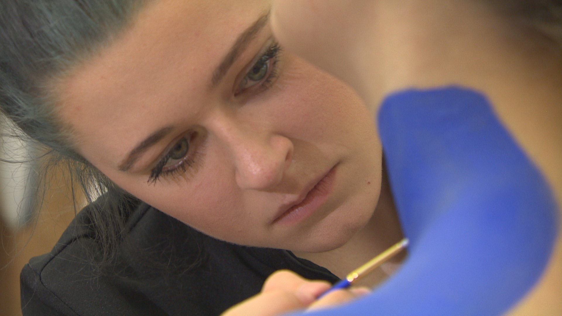 Miranda Klippenstein is focused as she paints details on her model's shoulder.