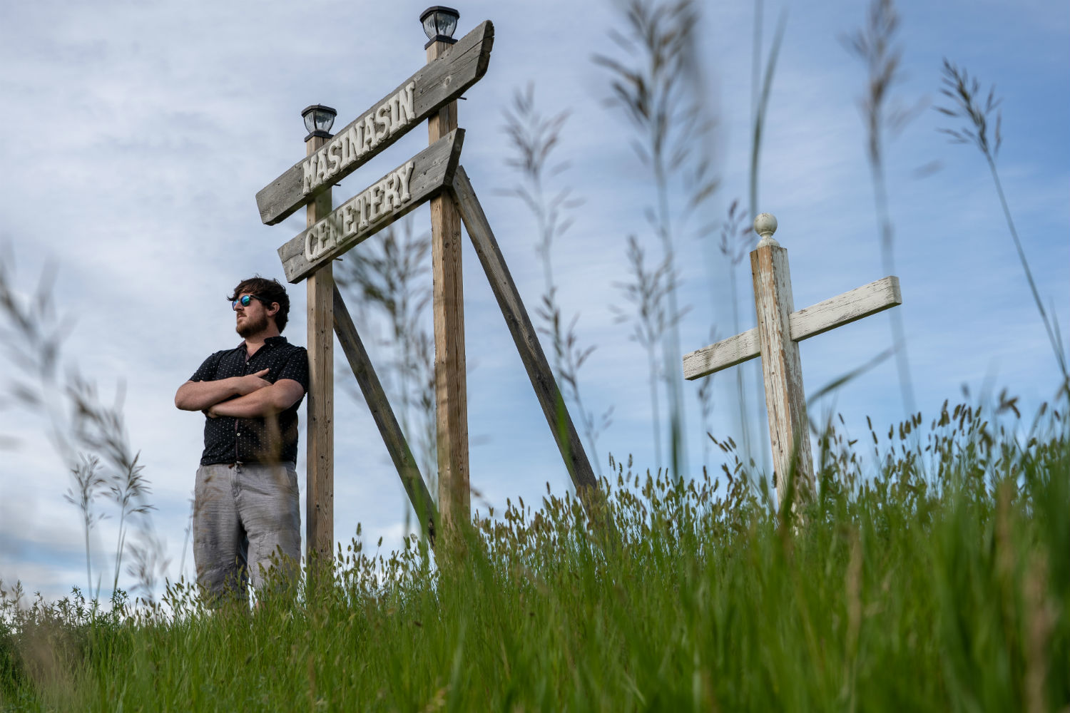 Cody Kapscos stands by a new sign for the old Masinasin Cemetery in southern Alberta. He took it upon himself to restore the small graveyard after coming across long-forgotten headstones in a field. (Vincent Bonnay/Radio-Canada)