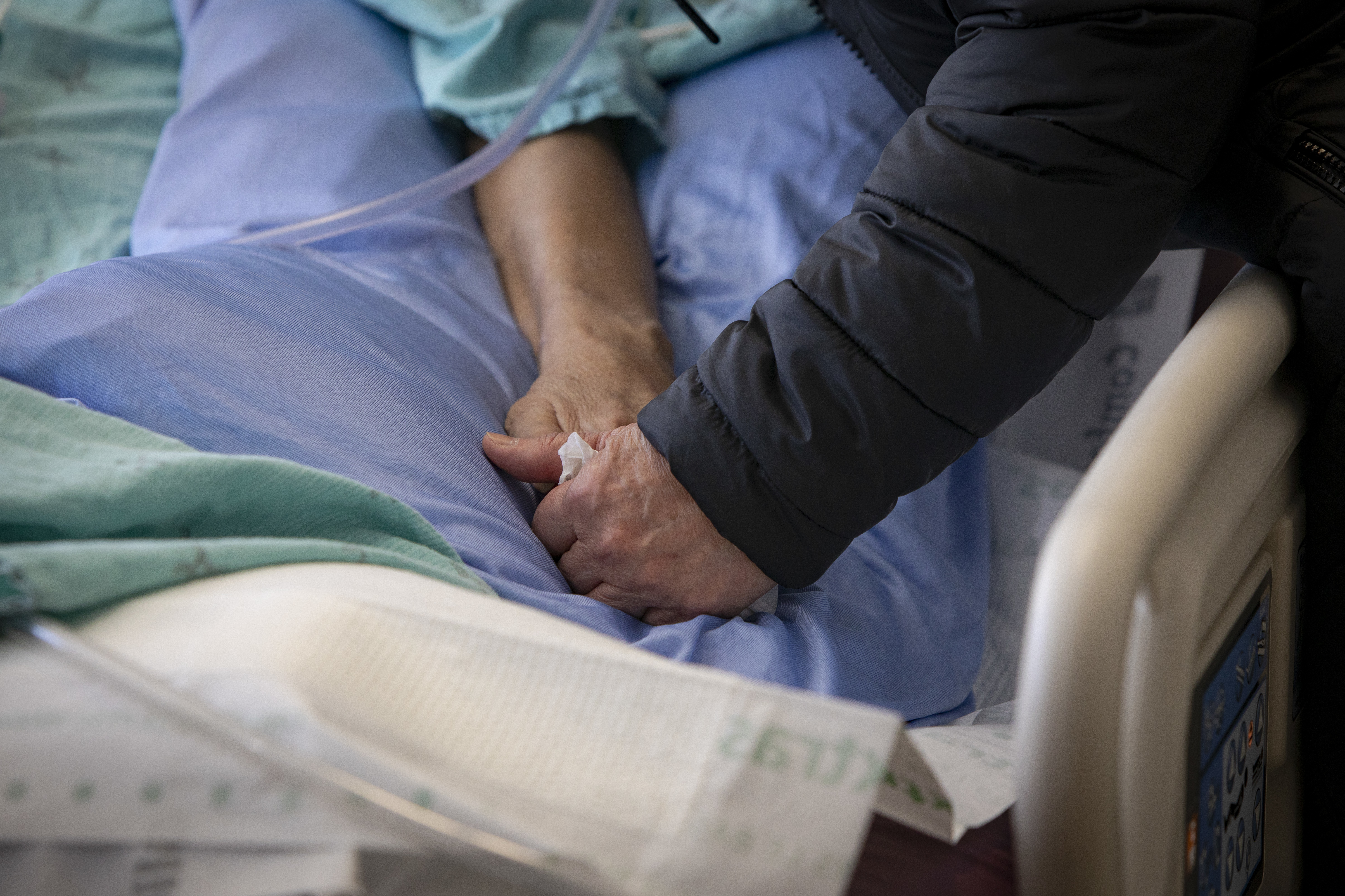 Esther Teodoro holds her husband Eduardo's hand while he's in his hospital bed at the Centenary Hospital intensive care unit. (Evan Mitsui/CBC News)