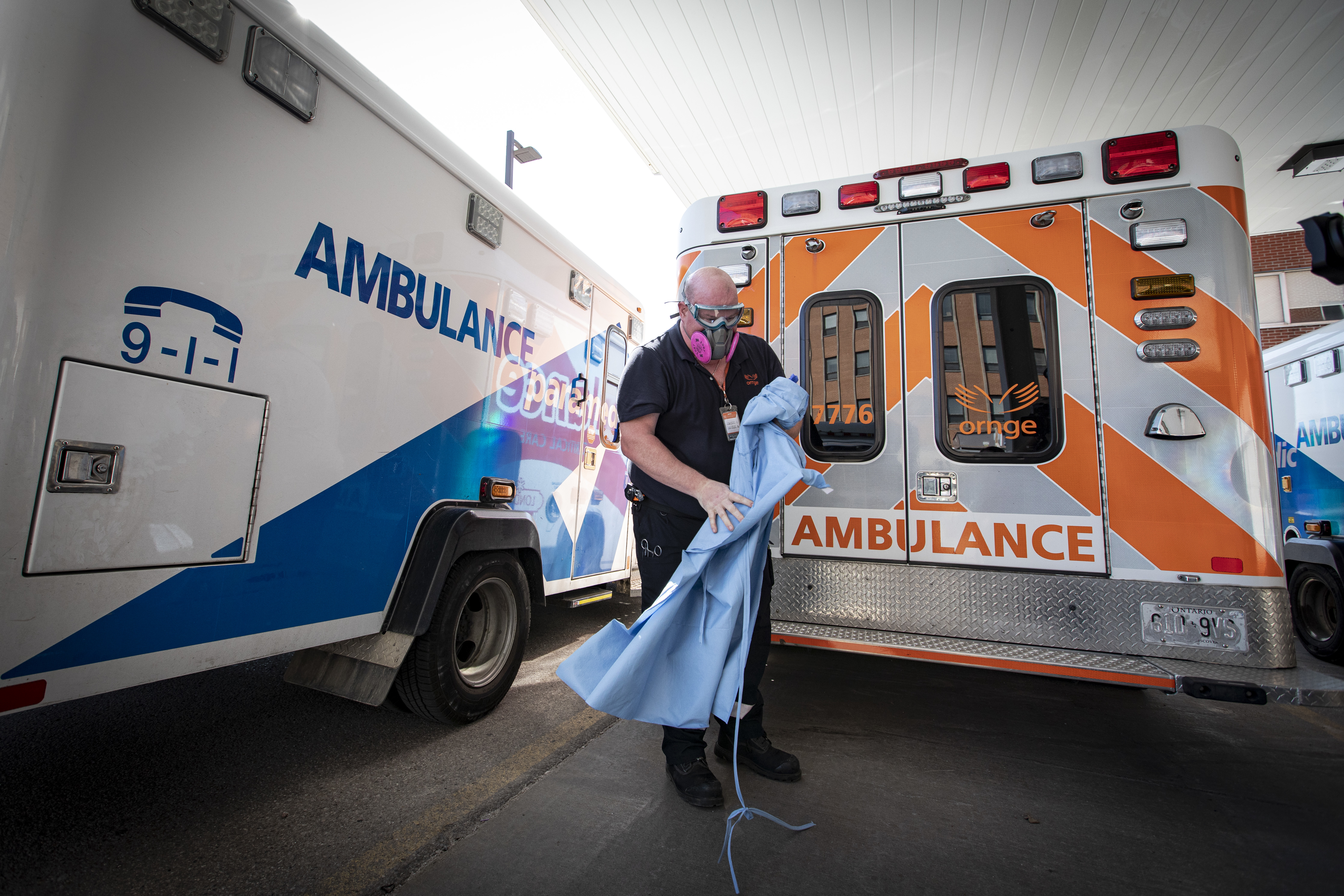 An Ornge paramedic removes a layer of PPE after loading an intubated COVID-19 patient into a waiting ambulance for a transfer to a nearby children's hospital. (Evan Mitsui/CBC)