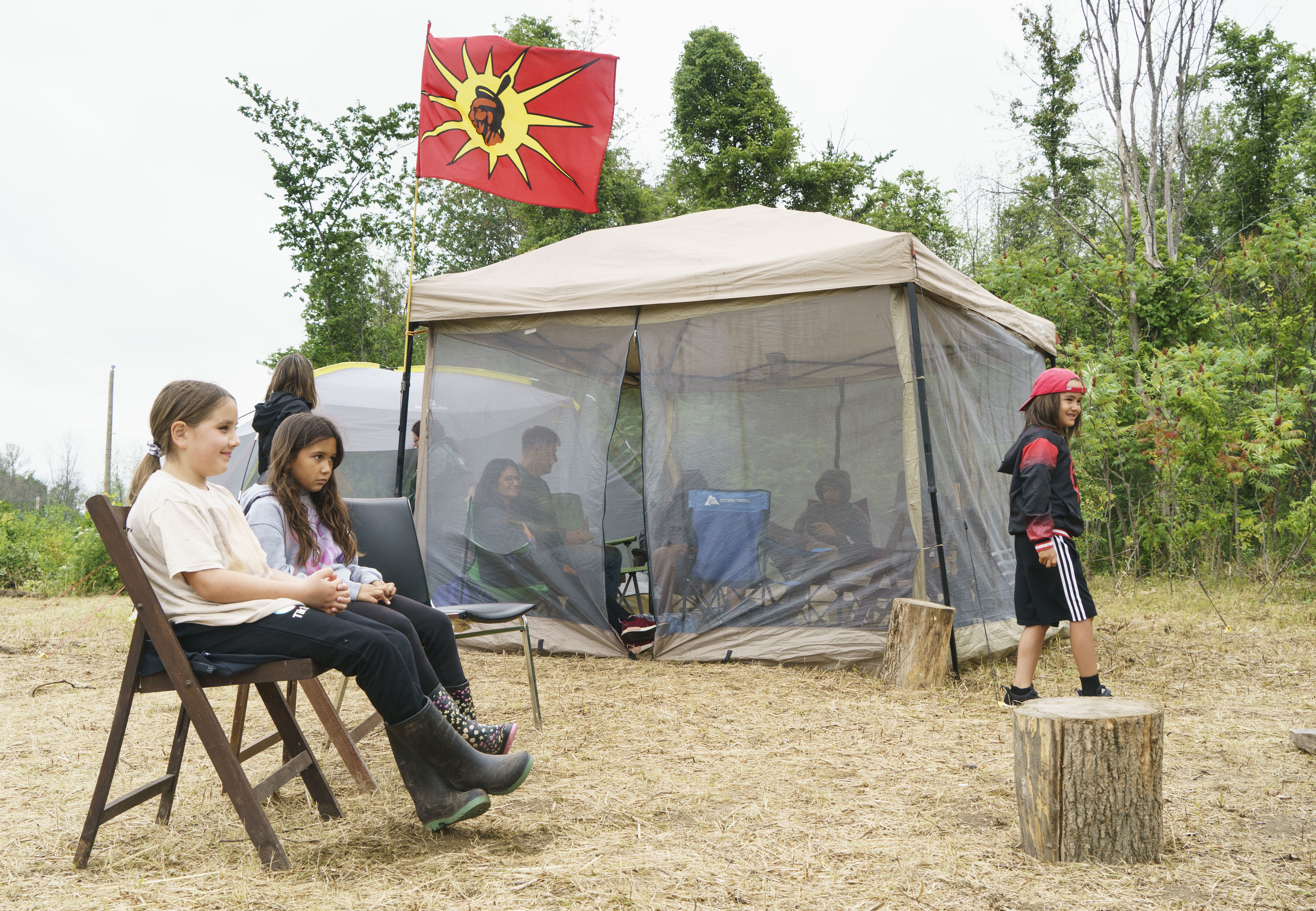 Children sit in a camp in Kahnawake next to where community members are occupying a disputed parcel of land to stop a proposed housing project on July 8. (Paul Chiasson/Canadian Press)