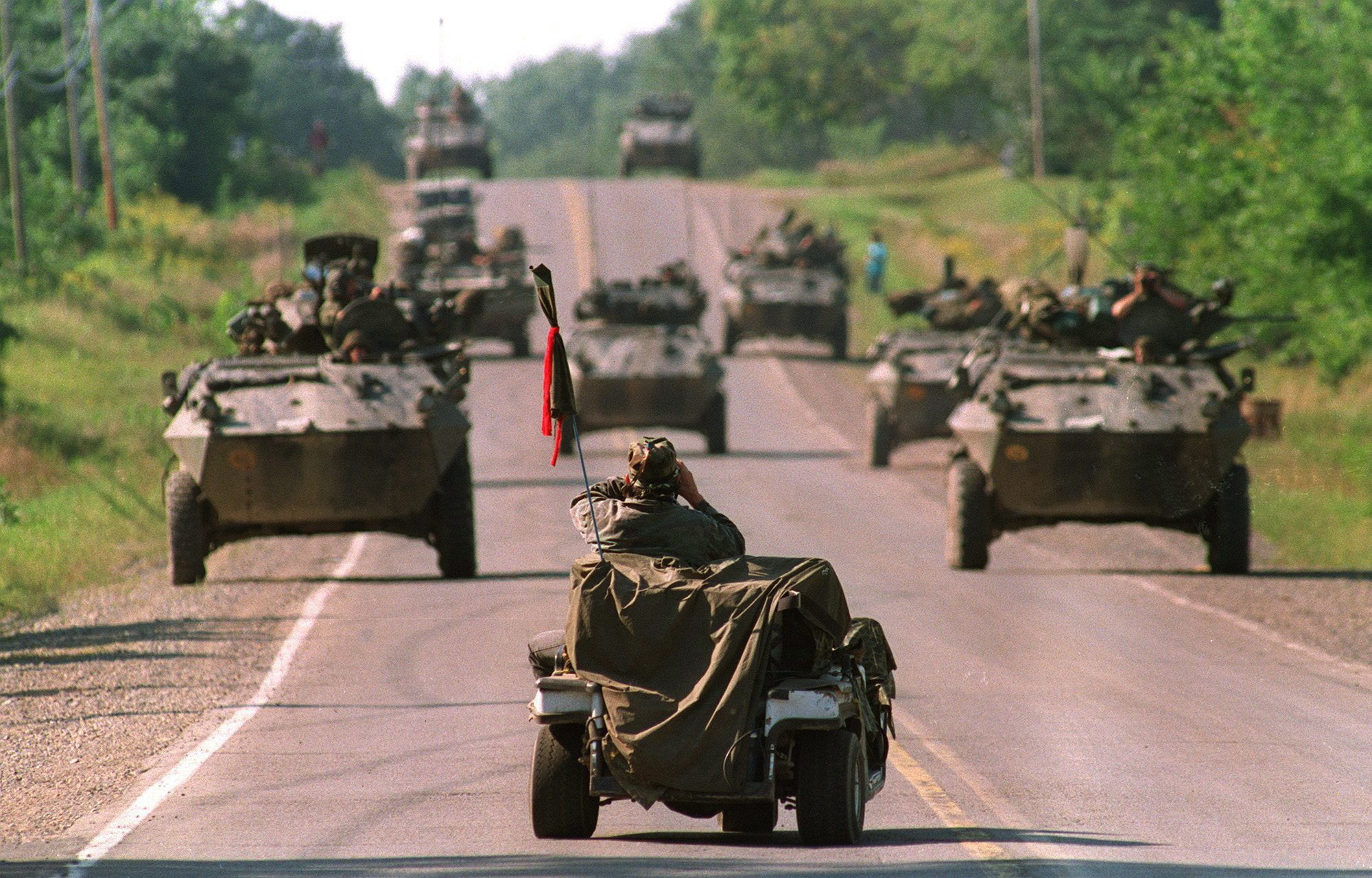 A Mohawk Warrior sits in a golf cart and uses binoculars to view approaching Canadian army armoured vehicles on Highway 344 in Kanesatake, Que., on Sept. 1, 1990. (Tom Hanson/Canadian Press))