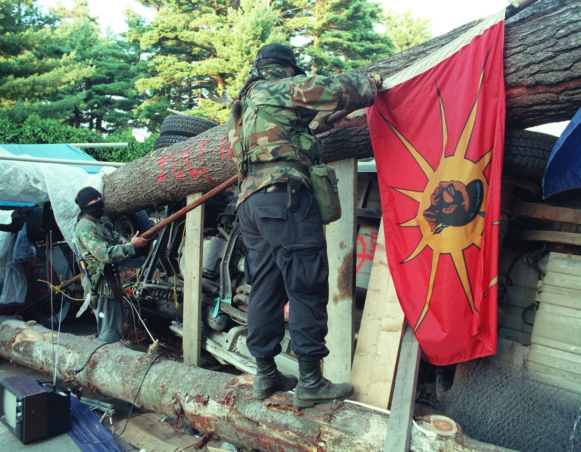 Two masked Mohawk Warriors remove a flag from the main barricade at Oka, Que., September 1, 1990, in order to keep it from falling into the hands of Canadian army. (Tom Hanson/The Canadian Press)