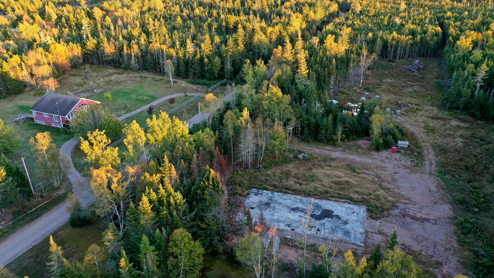 The burned-out patch of grass shows where Gabriel Wortman's garage used to be — directly across the road from Lisa McCully's red house. (Steve Lawrence/CBC)