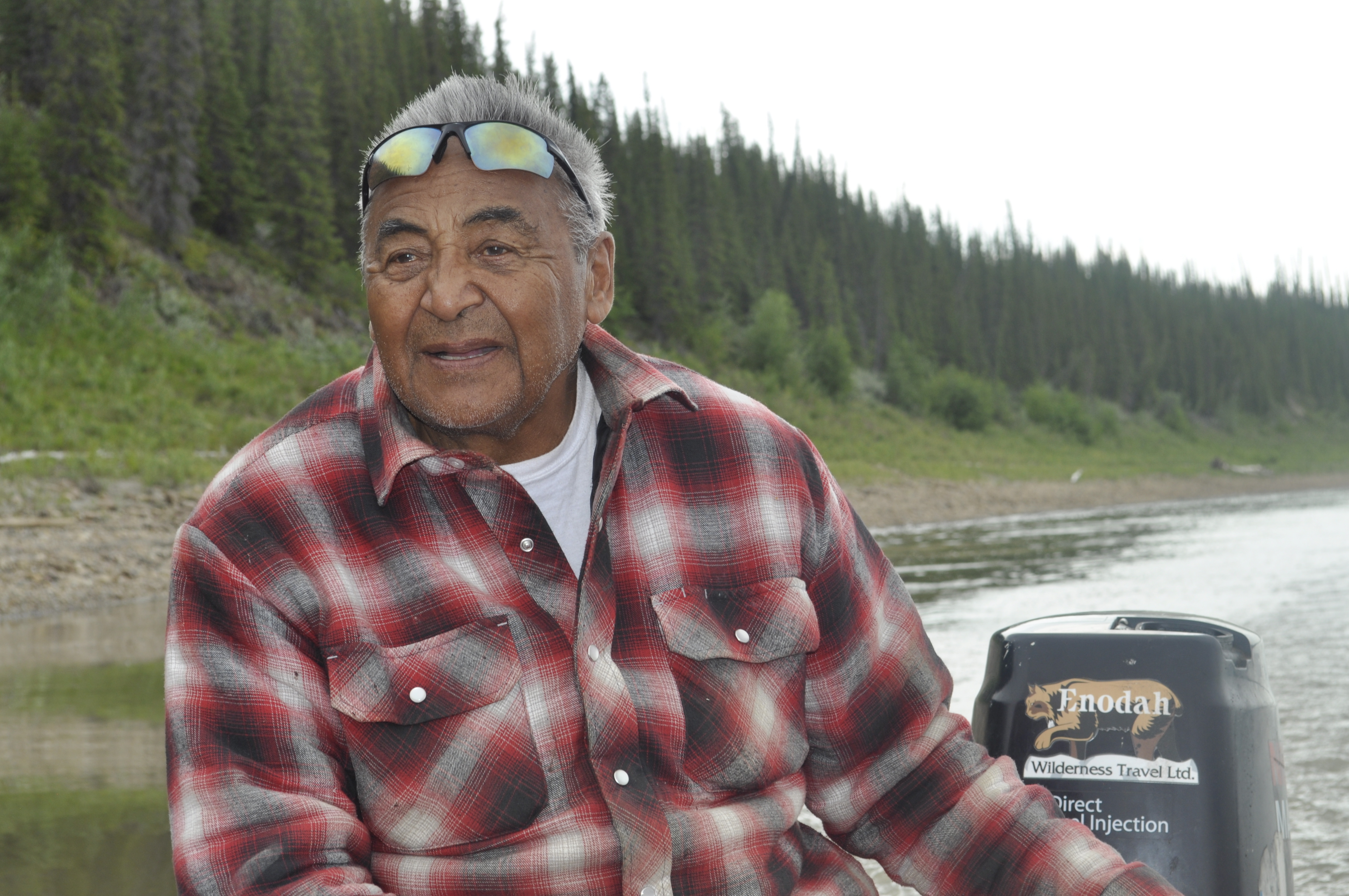 Wilfred Jackson steers his boat on the Mackenzie River. He's spent most of the past 80 summers on the river and knows how it's been changing. (Alex Brockman/CBC)