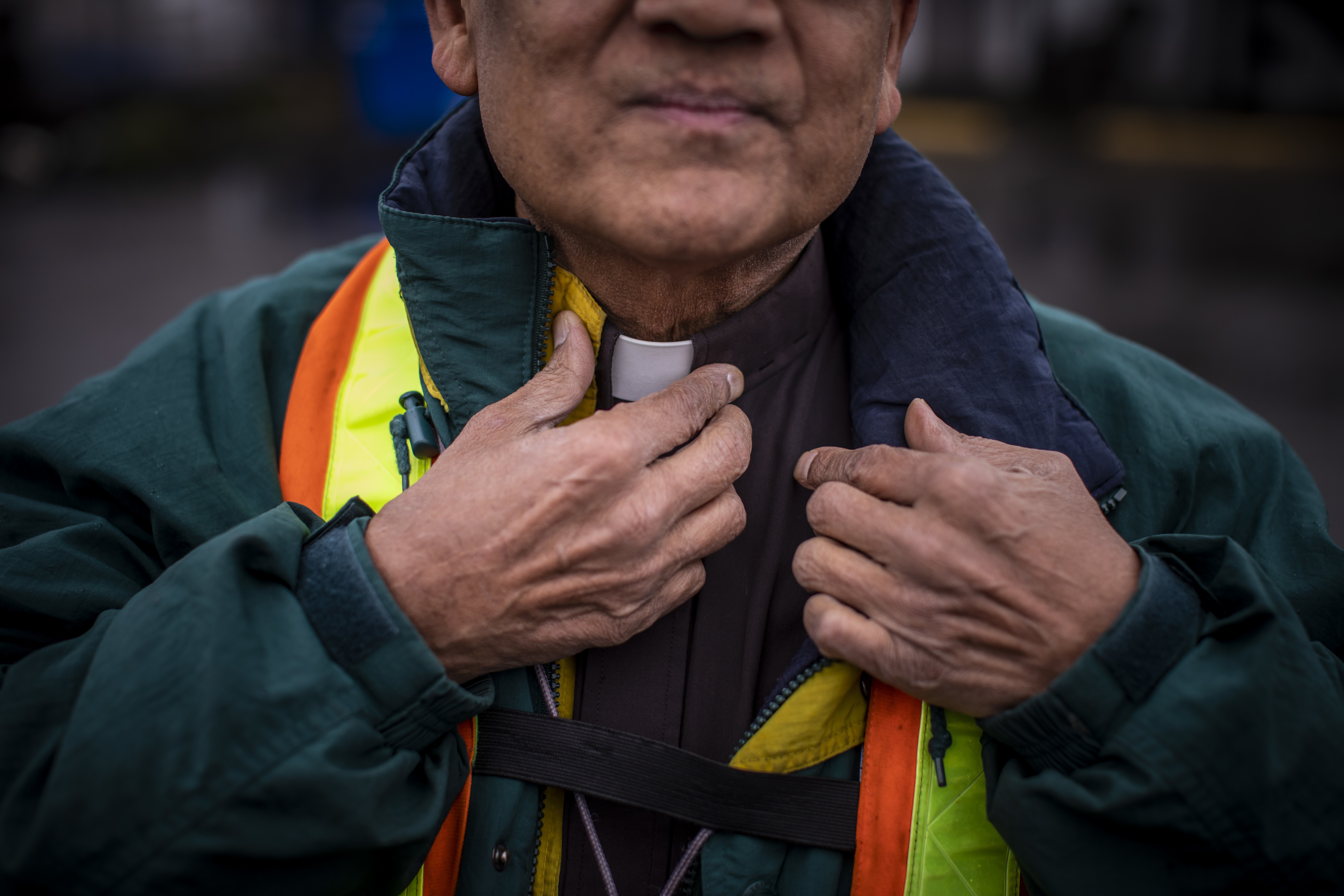 Deacon Athaide adjusts his collar while also wearing safety equipment that is mandatory when working at the port.