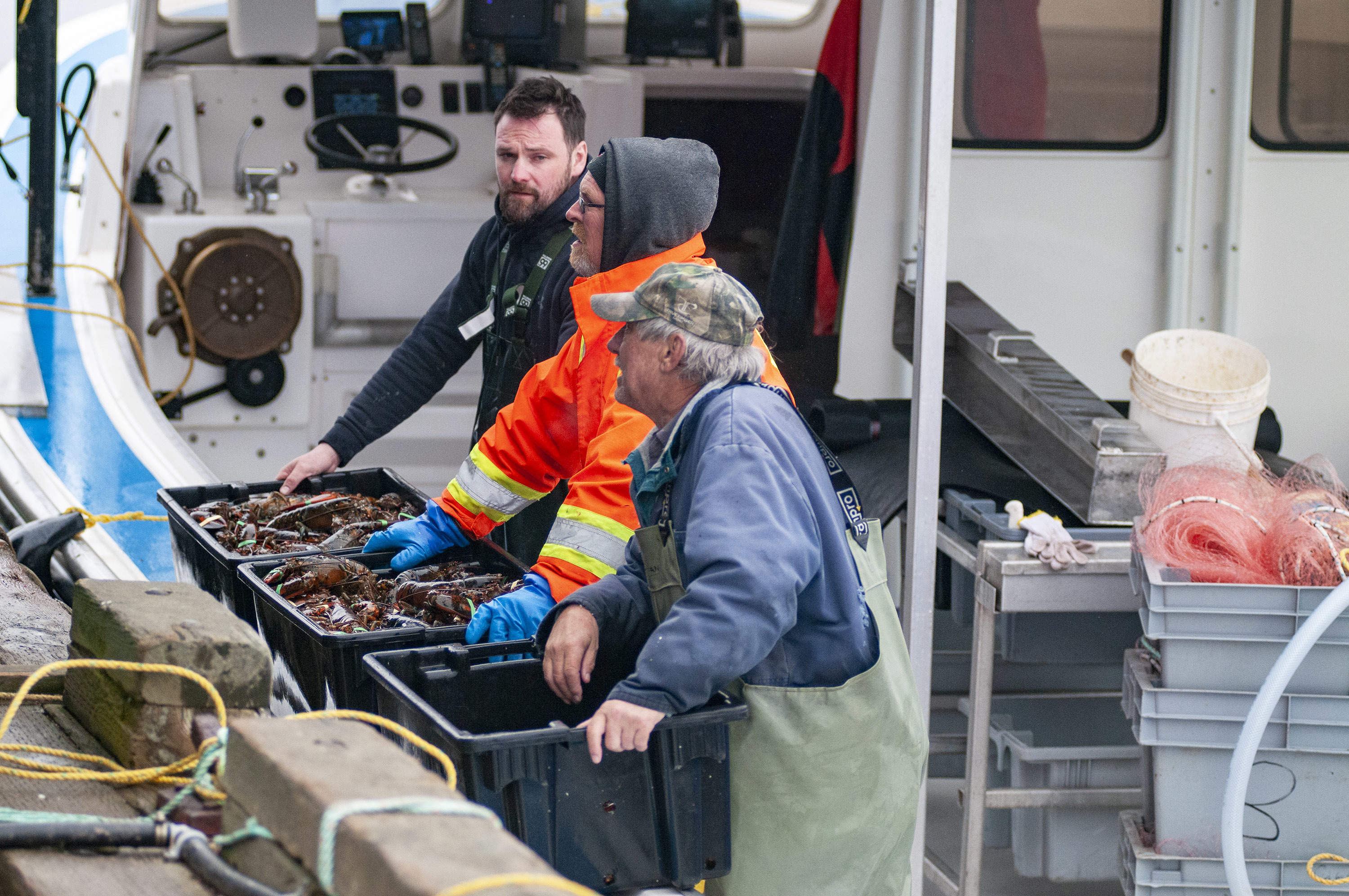 Scott McAleese, left, Andy MacLeod and David MacLeod, crew of Island Morning wait to offload their cargo of lobster. (Brian McInnis)