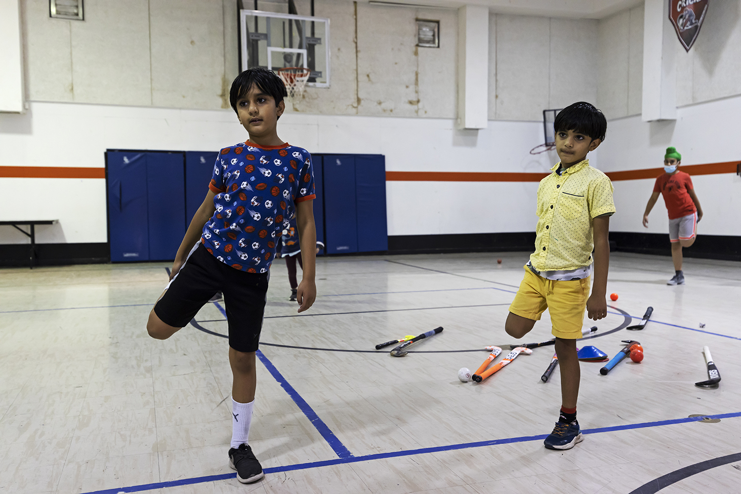 Kartik Trivedi, 8, and Kovid Trivedi, 7, stretch as part of their warm-up before they get to play with the field hockey sticks. 