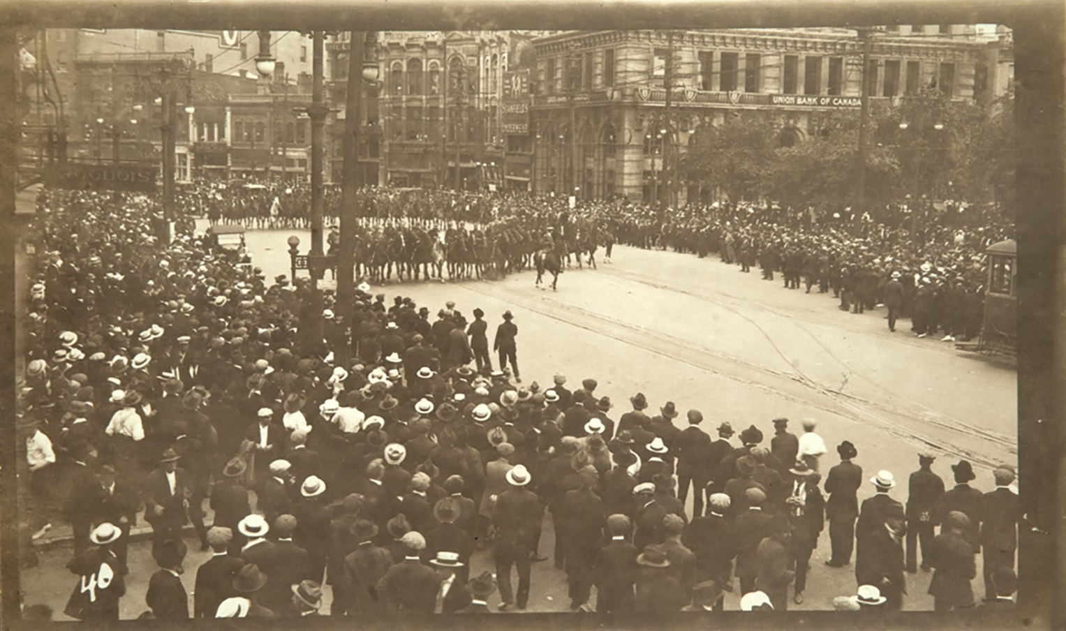 Mounties on horseback push the crowd back from the burning streetcar. (L.B. Foote Collection/Archives of Manitoba)