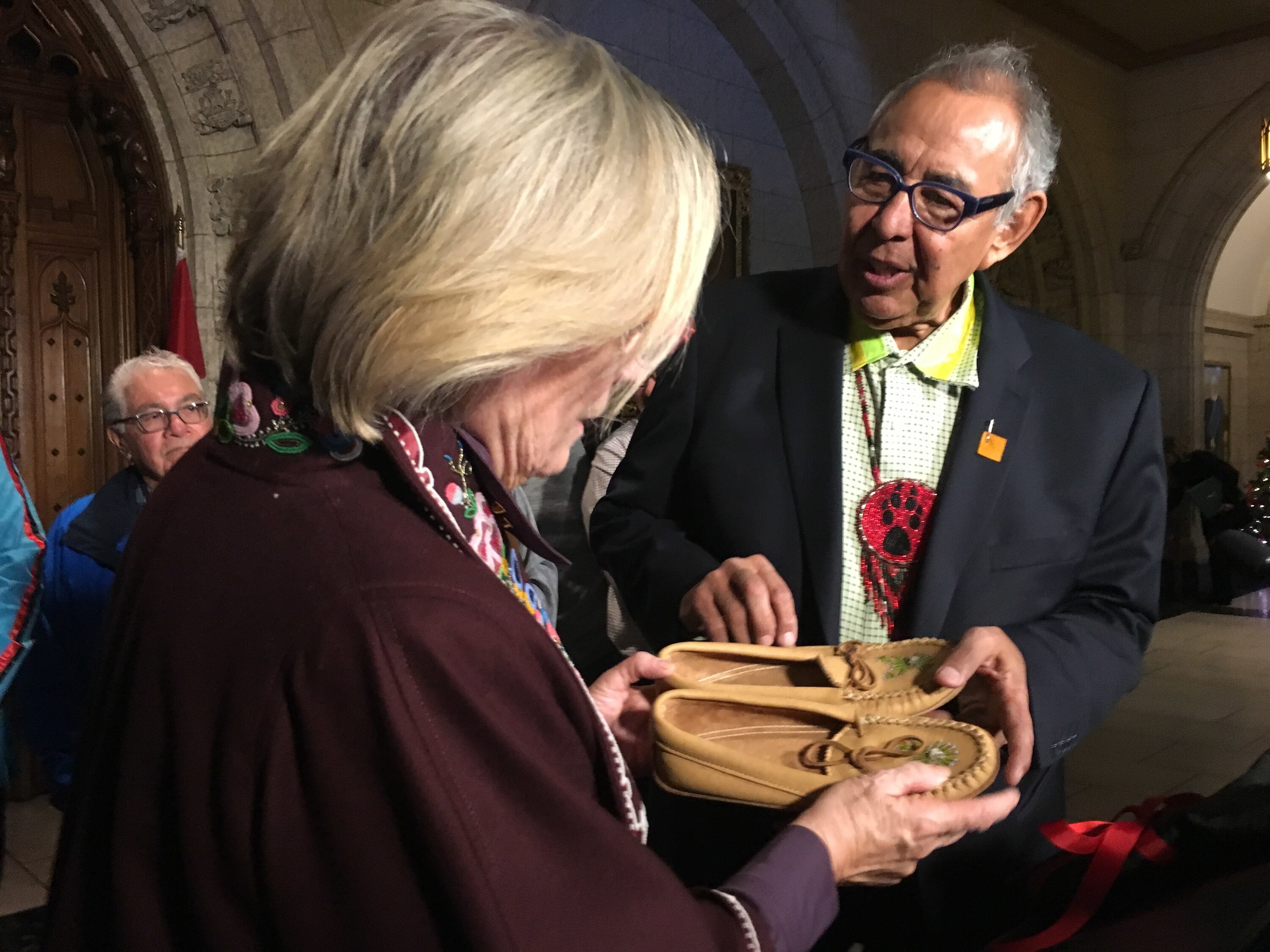 Garry McLean, the lead plaintiff in the Indian day schools court action, presents moccasins to Crown-Indigenous Relations Minister Carolyn Bennett after the announcement of an agreement in principle in December 2018. (Jorge Barrera/CBC)