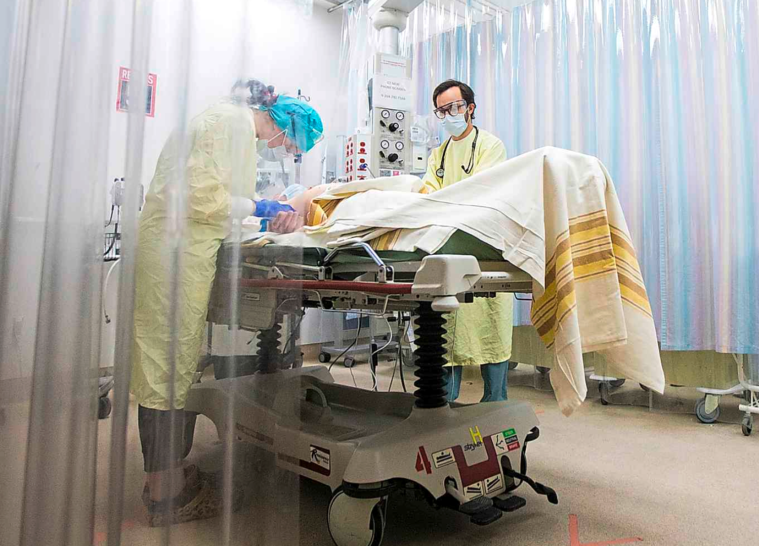 A resuscitation patient receives care in the emergency department. Every bed is now separated by a plastic barrier as hospital staff treat every new admission like a presumed COVID-positive patient. (Mikaela MacKenzie/Winnipeg Free Press/Canadian Press)