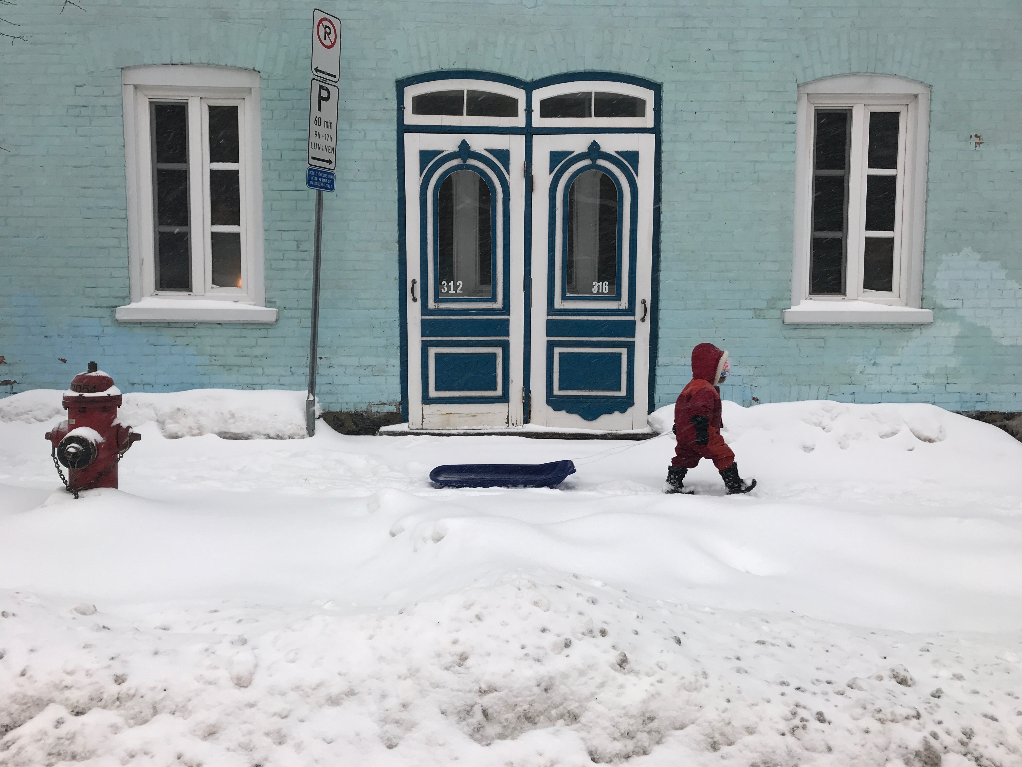 A child pulls a plastic sled while walking through Quebec City's Saint-Jean-Baptiste neighbourhood. (Julia Caron/CBC)