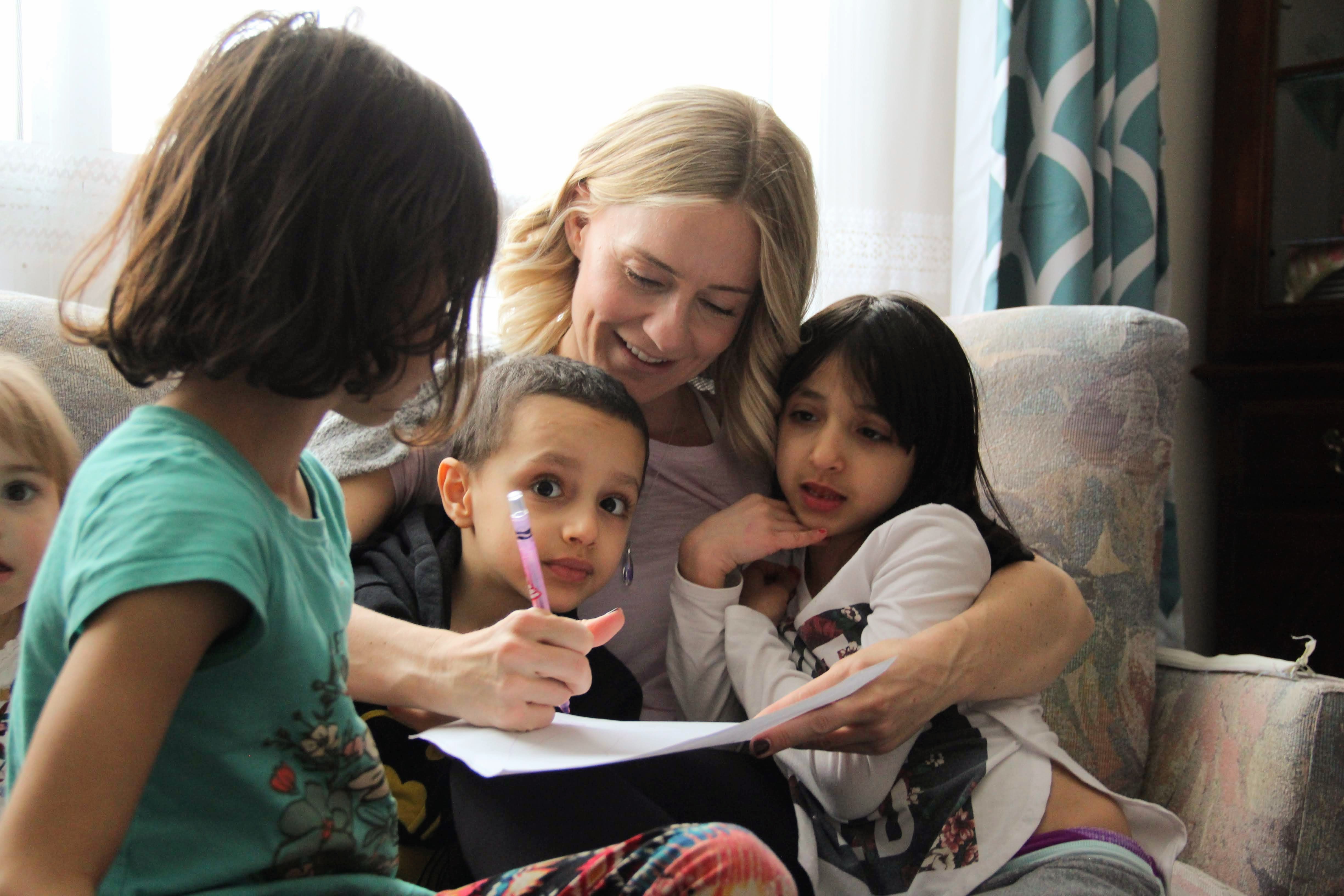 Vicki Melo draws three of the Alsliman children around her during a recent visit to their place.