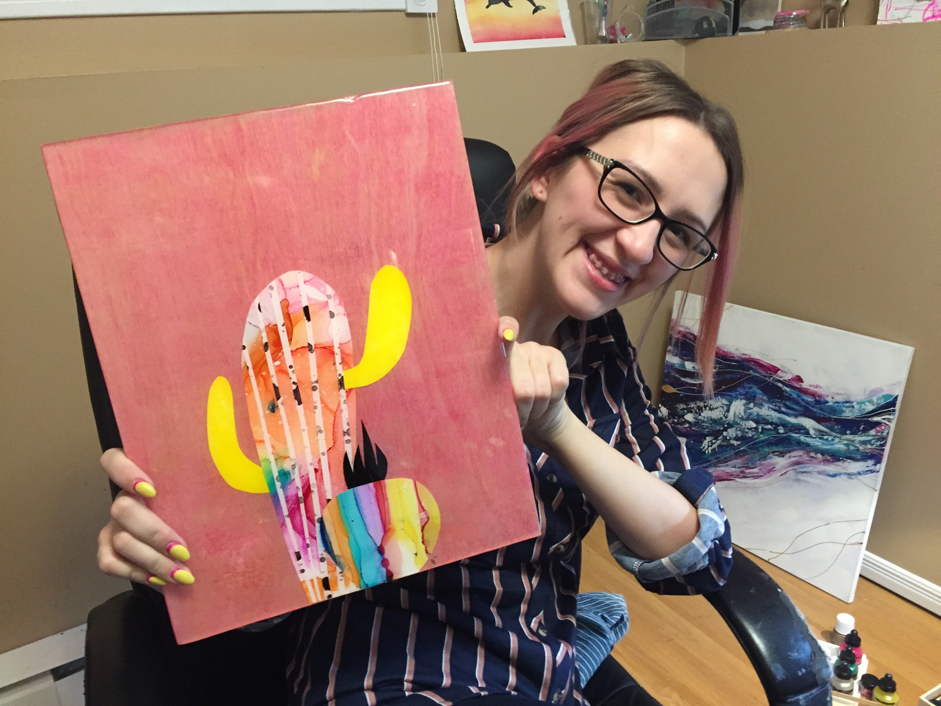 Sara Dillon holds up one of her more recent creations: an alcohol-printed layered painting. (Stephanie Tobin/CBC)