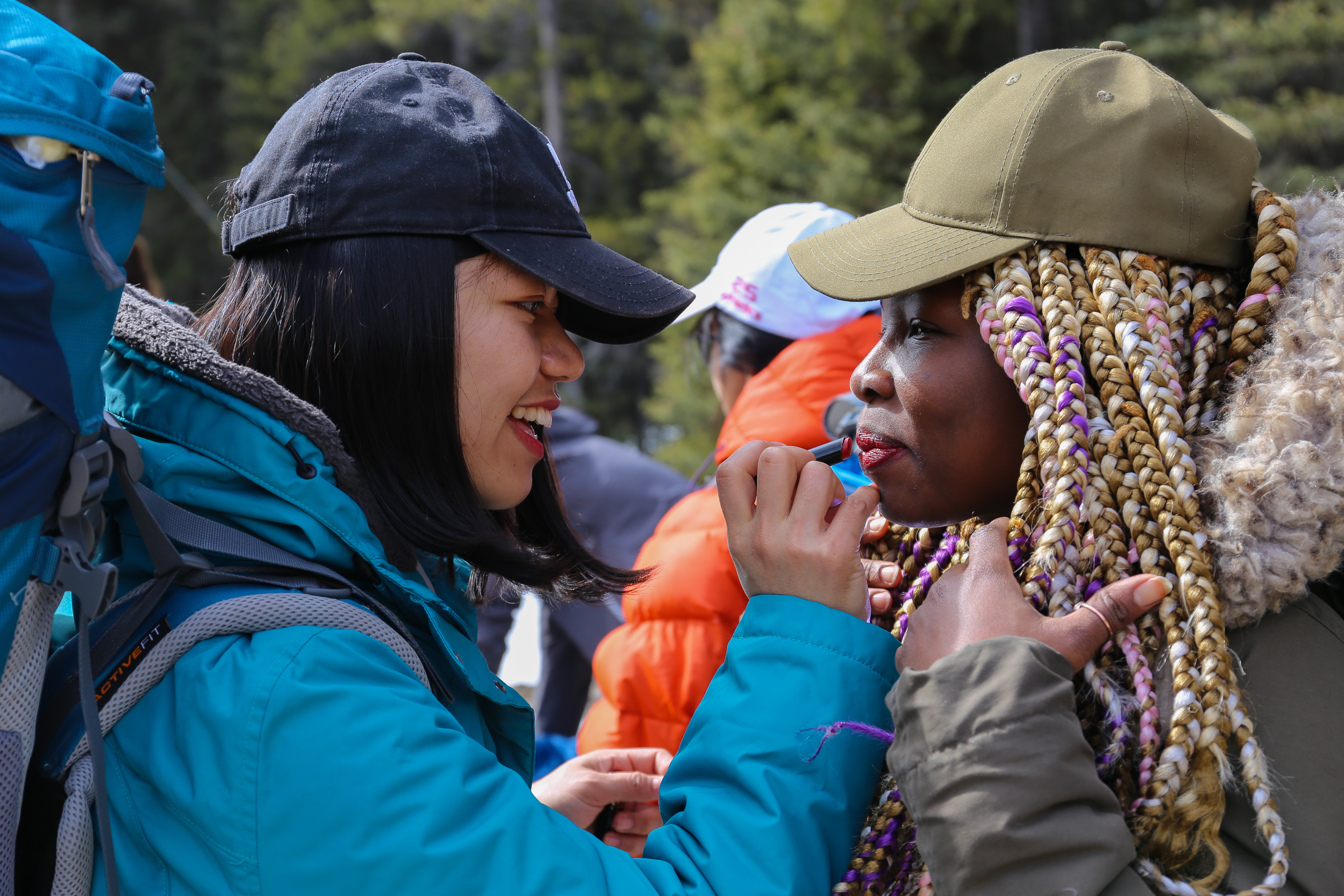 Ciang Uap helps Aimee Mugisha apply lipstick before they begin hiking. (Emily Rendell-Watson/CBC)