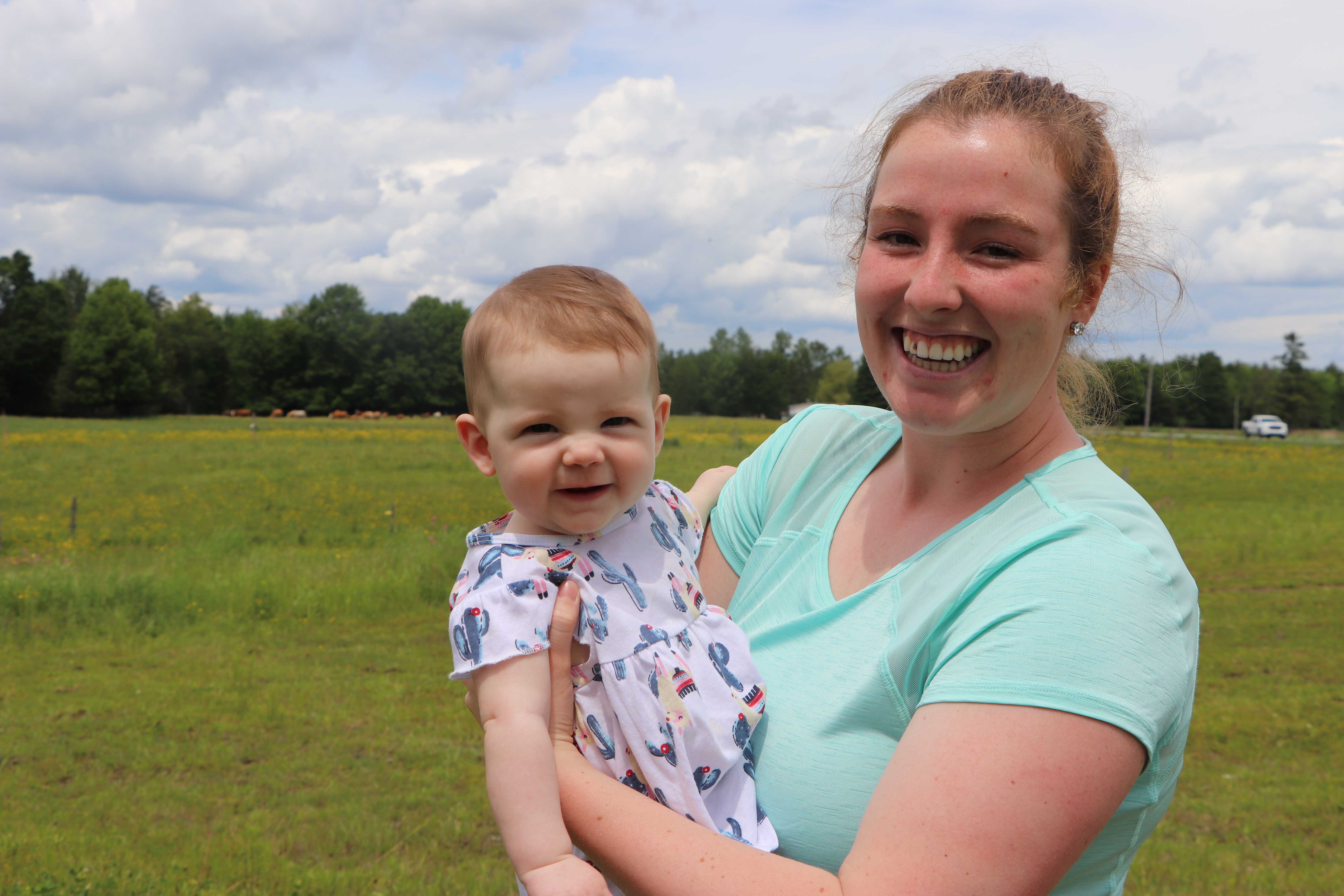 Shelby Drew Harrison and 6-month-old Kynlee stand in the field at Apple Ridge Farm in Canton-de-Hatley. (Julia Page/CBC)