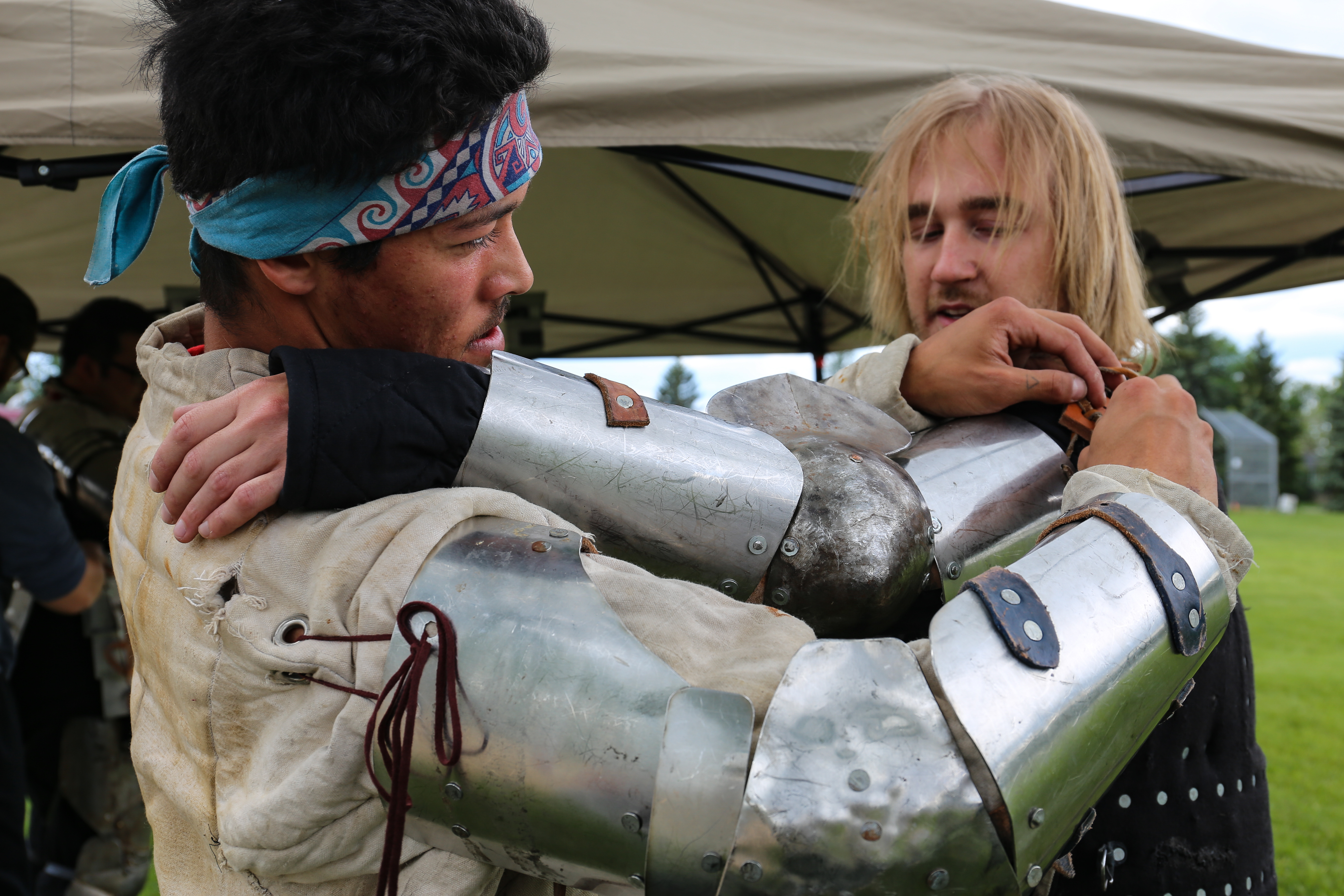 Logan Belcourt helps his teammate Rowan MacLauchlan put on armour at practice. (Emily Rendell-Watson/CBC)