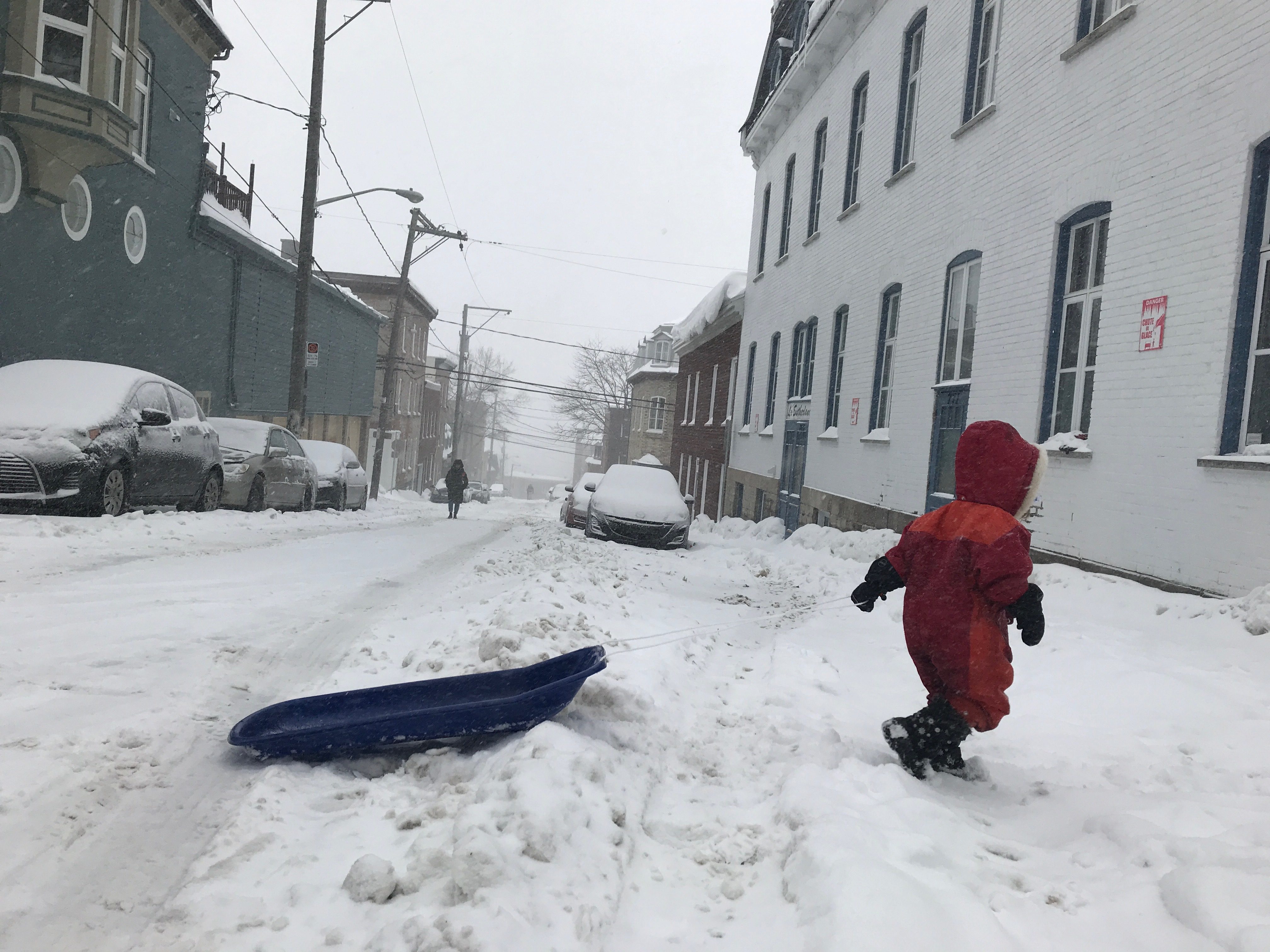 Two-and-a-half-year-old Marguerite Dumas carts her sled across one of the many snowy streets in the Saint-Jean-Baptiste area. (Julia Caron/CBC)