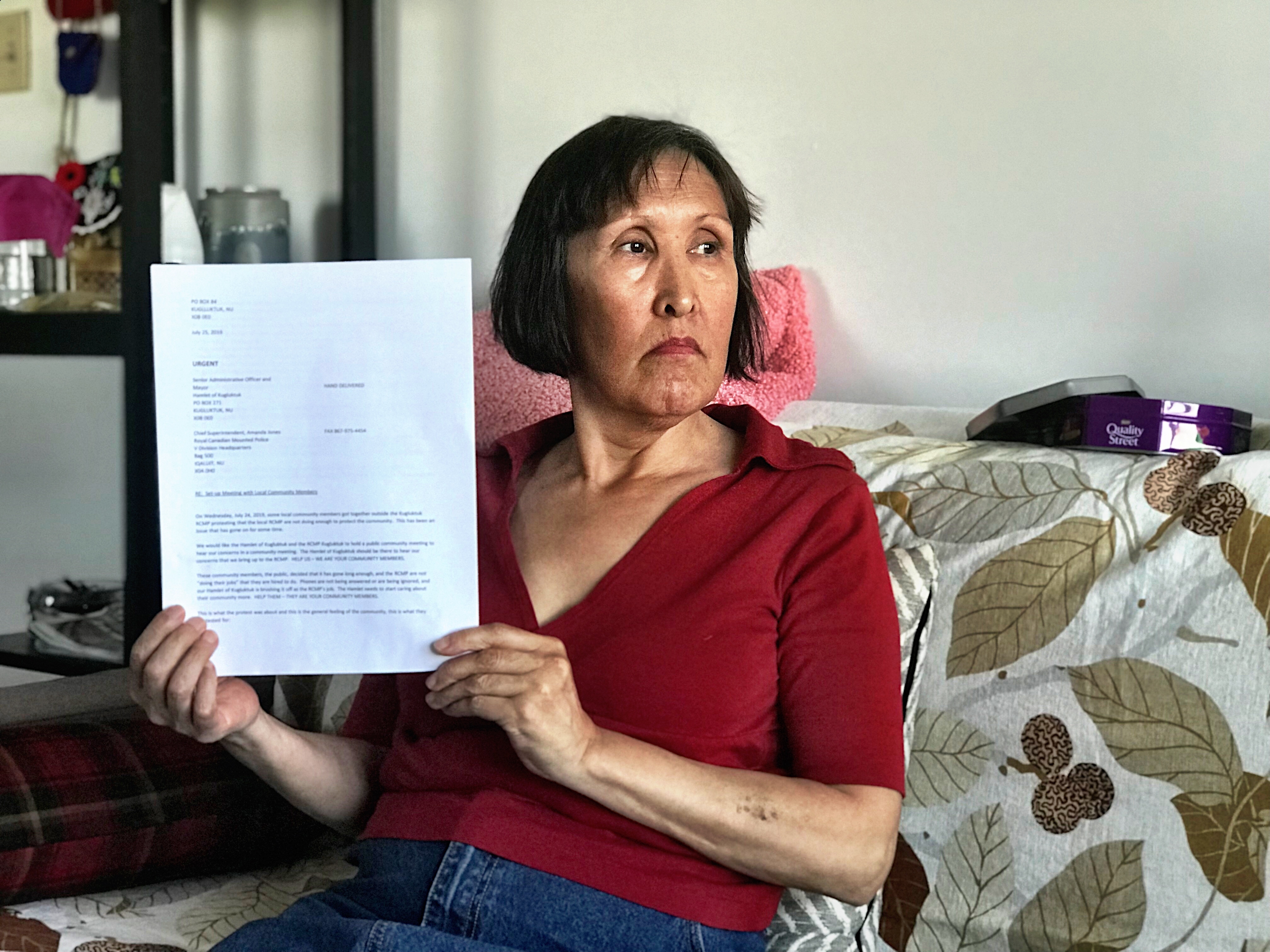 Barb Adjun holds up the letter she wrote RCMP and Nunavut officials calling for a public meeting. A week later, a dozen officials and the head of Nunavut's RCMP Division were in the community to hear the public's concerns. (Hilary Bird/CBC)