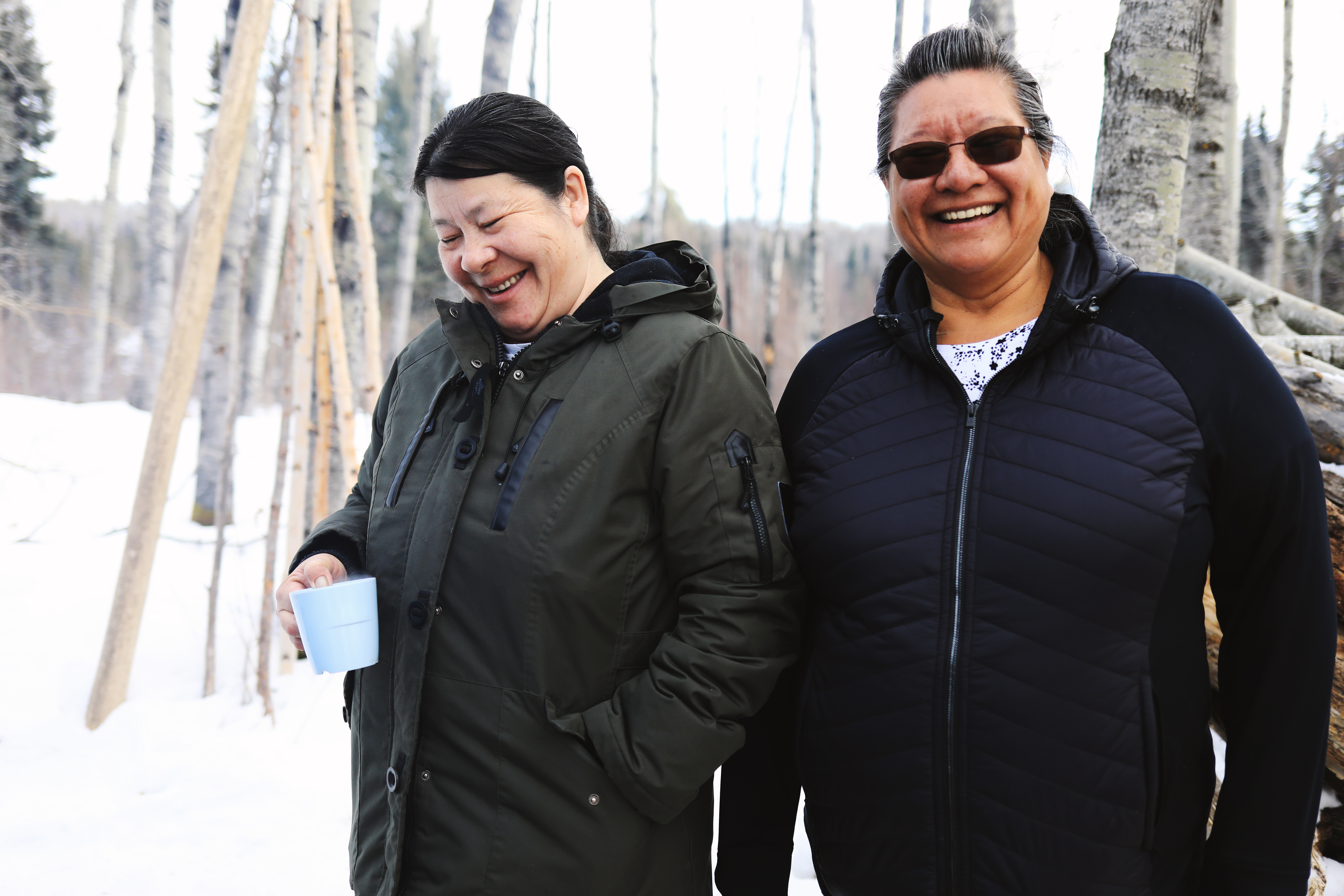 Susan McLeod and Isabelle Hardlotte share a laugh out at the school system's land-based education site. Hardlotte said she would stay out in nature all day if she could. (Heidi Atter/CBC)