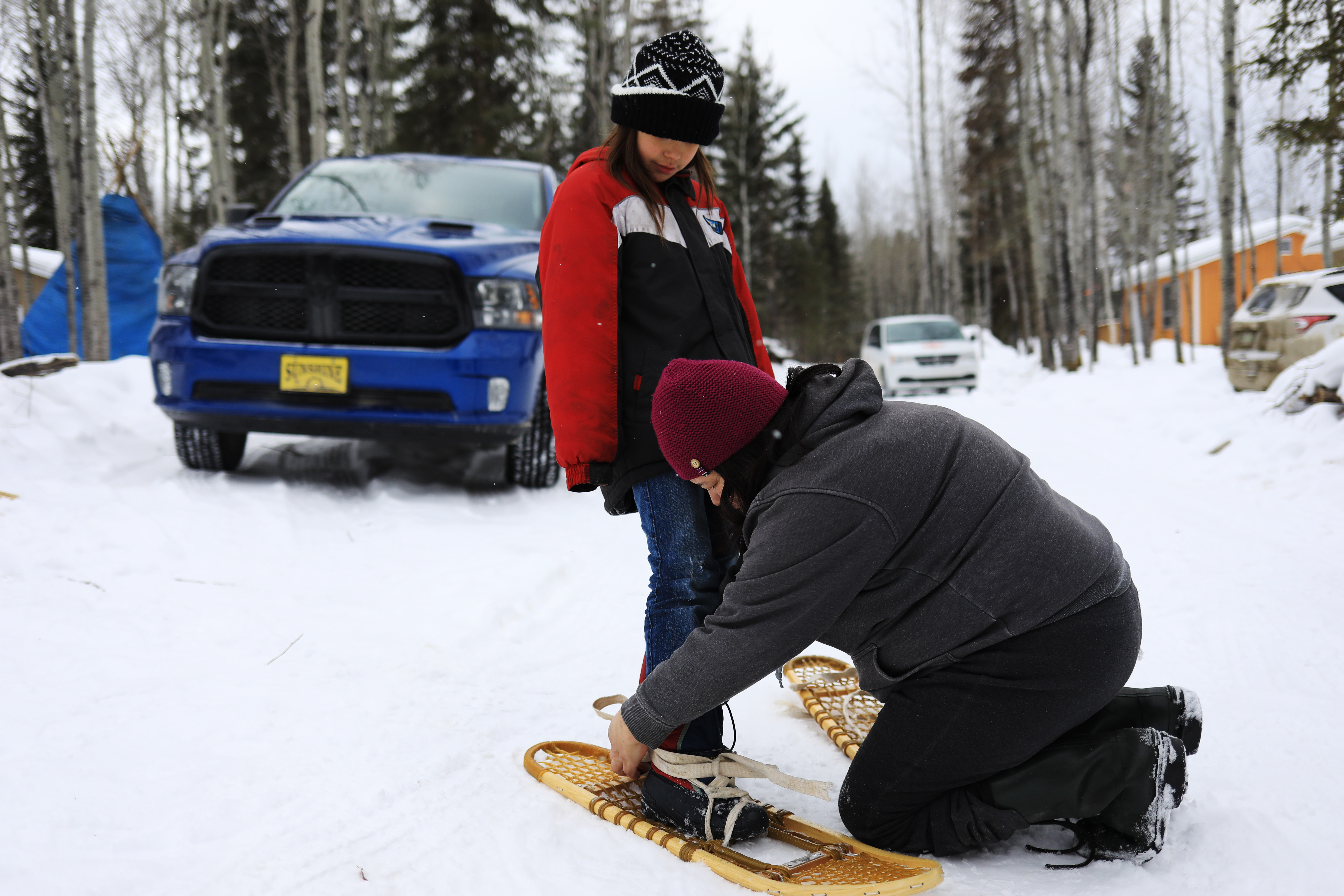 Sylvia Mckenzie helps Kiersten McLeod put on her showshoes properly. (Heidi Atter/CBC)