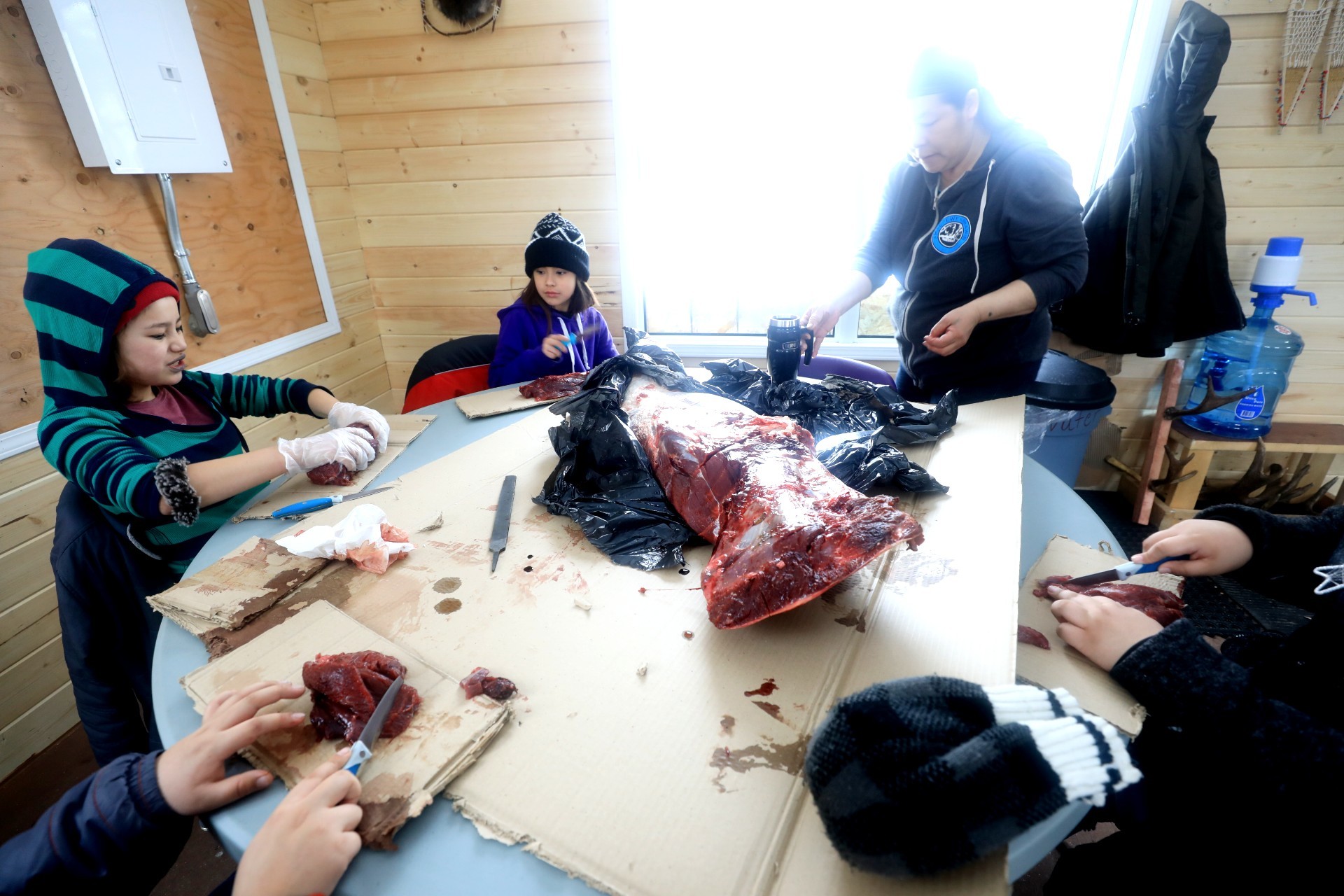 Children prepare moose meat in the kitchen. (Heidi Atter/CBC)