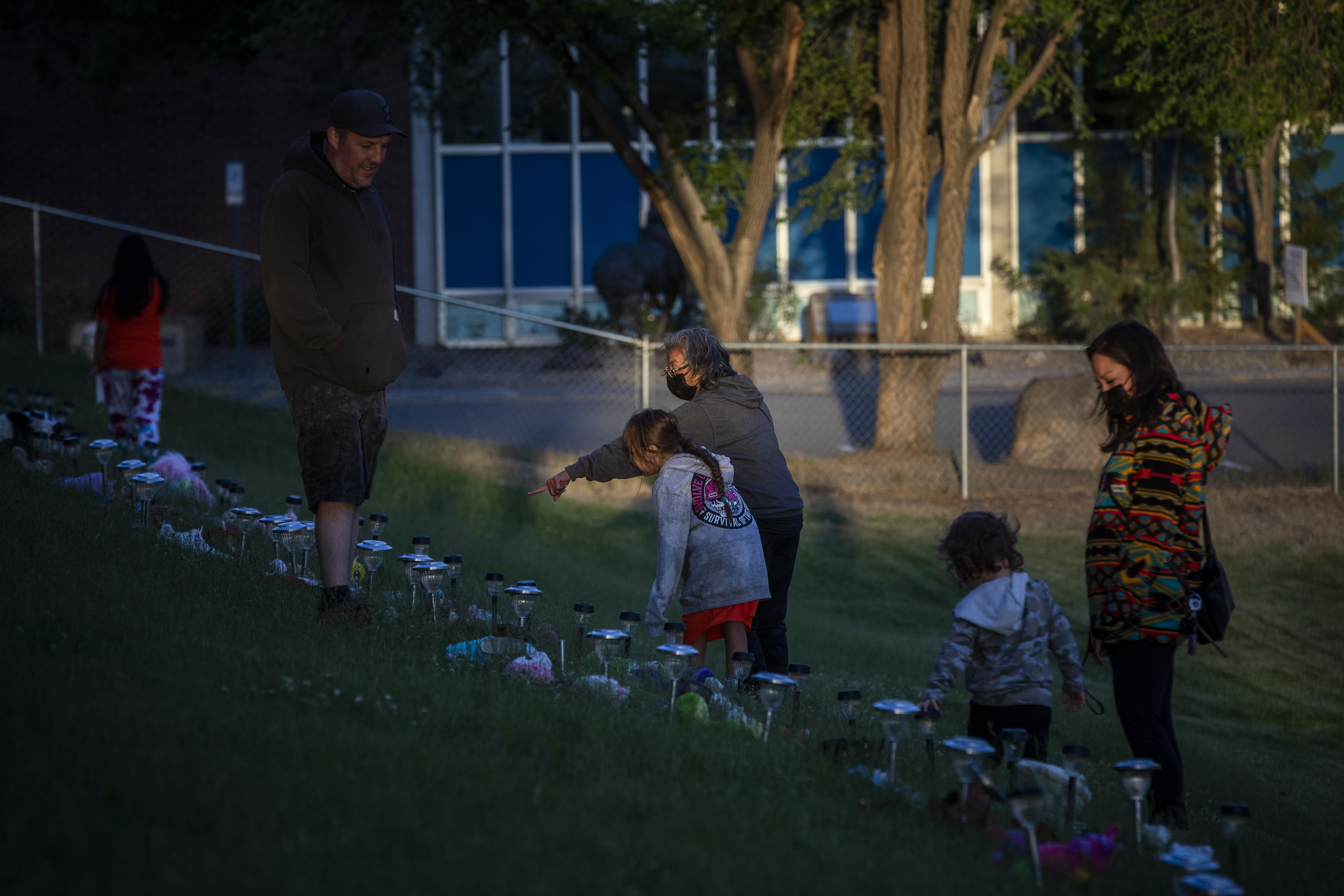 People are pictured reflecting at a memorial near the former Kamloops Indian Residential School.