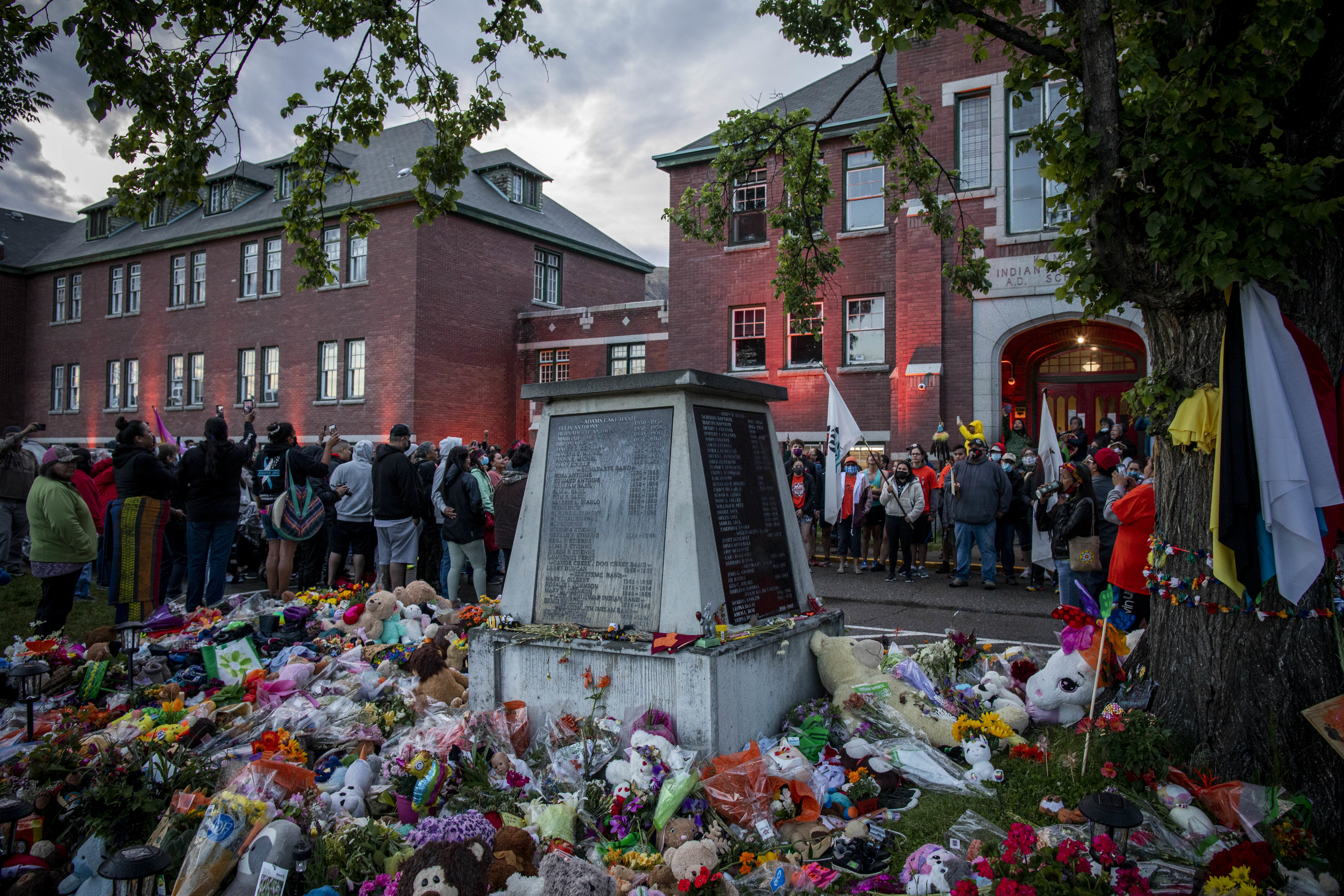 People gather outside the former Kamloops Indian Residential School after a short rainfall.