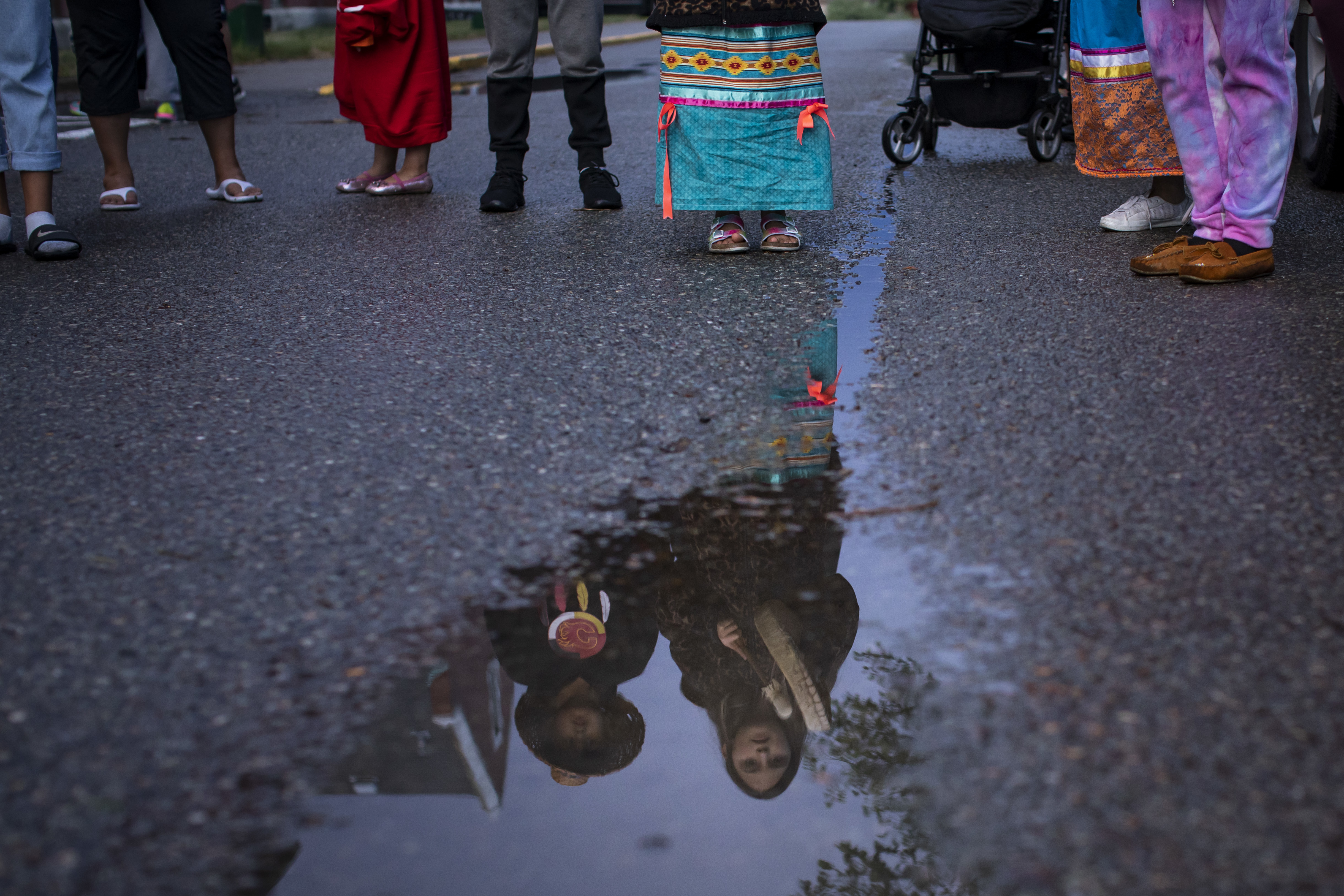 People gather outside the former Kamloops Indian Residential School as they welcome a group of runners from the Syilx Okanagan Nation taking part in The Spirit of Syilx Unity Run, an annual run to unify the community while addressing mental health and cultural rejuvenation.